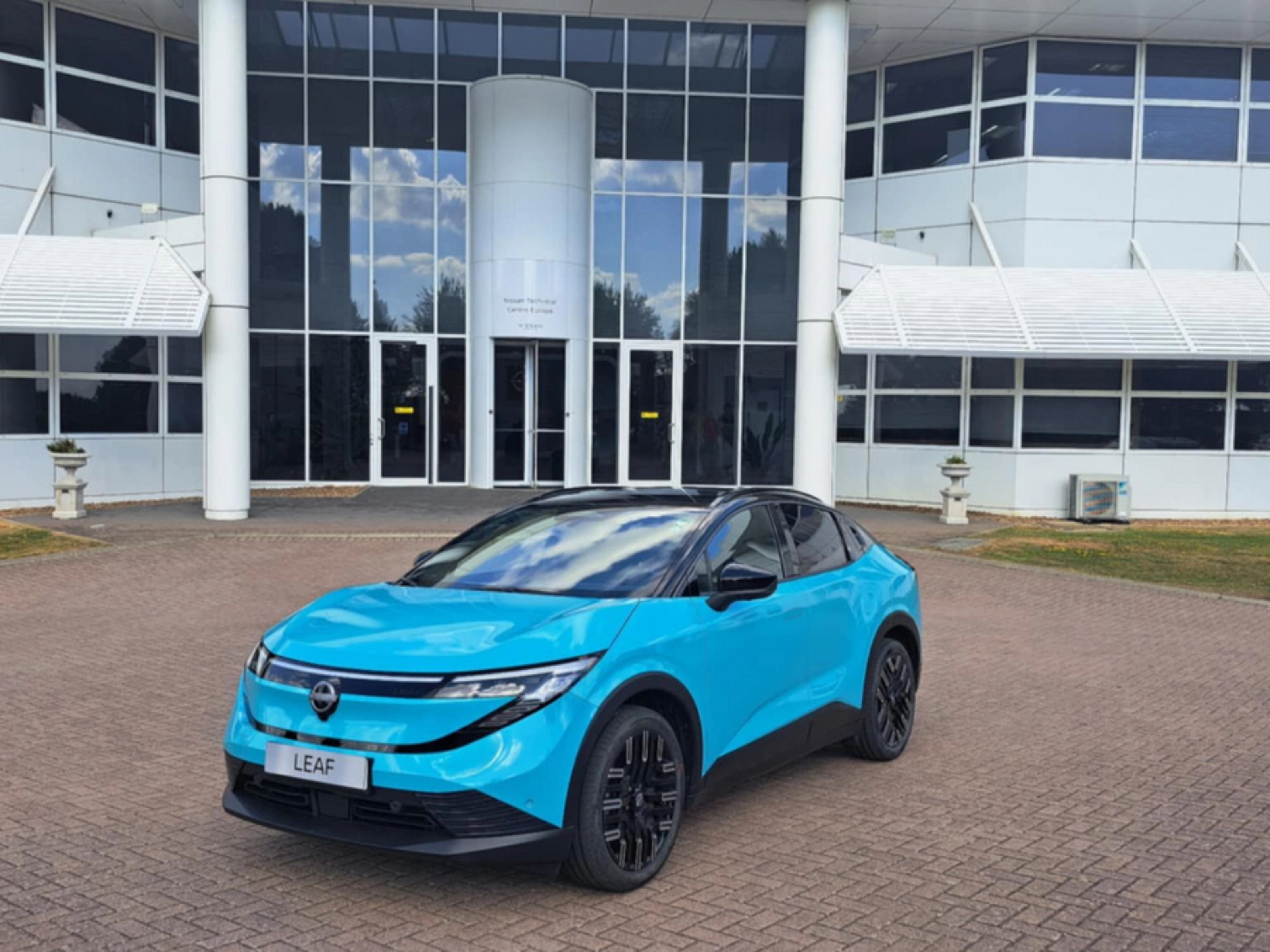 Blauer Nissan Crossover steht vor einem modernen Gebäude mit Glasfassade.