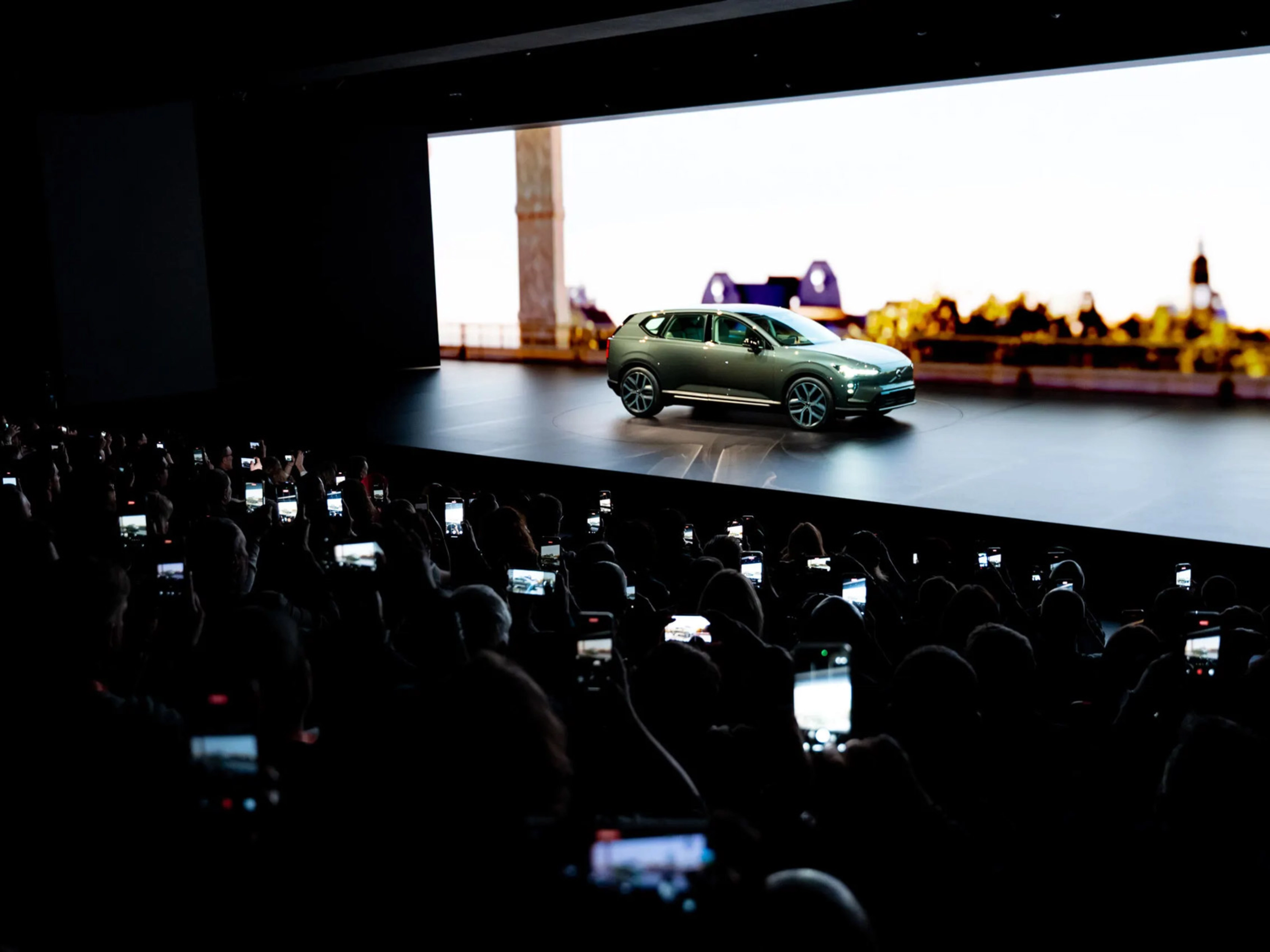 Elektrischer SUV wird auf einer Bühne präsentiert, das Publikum fotografiert mit Smartphones.