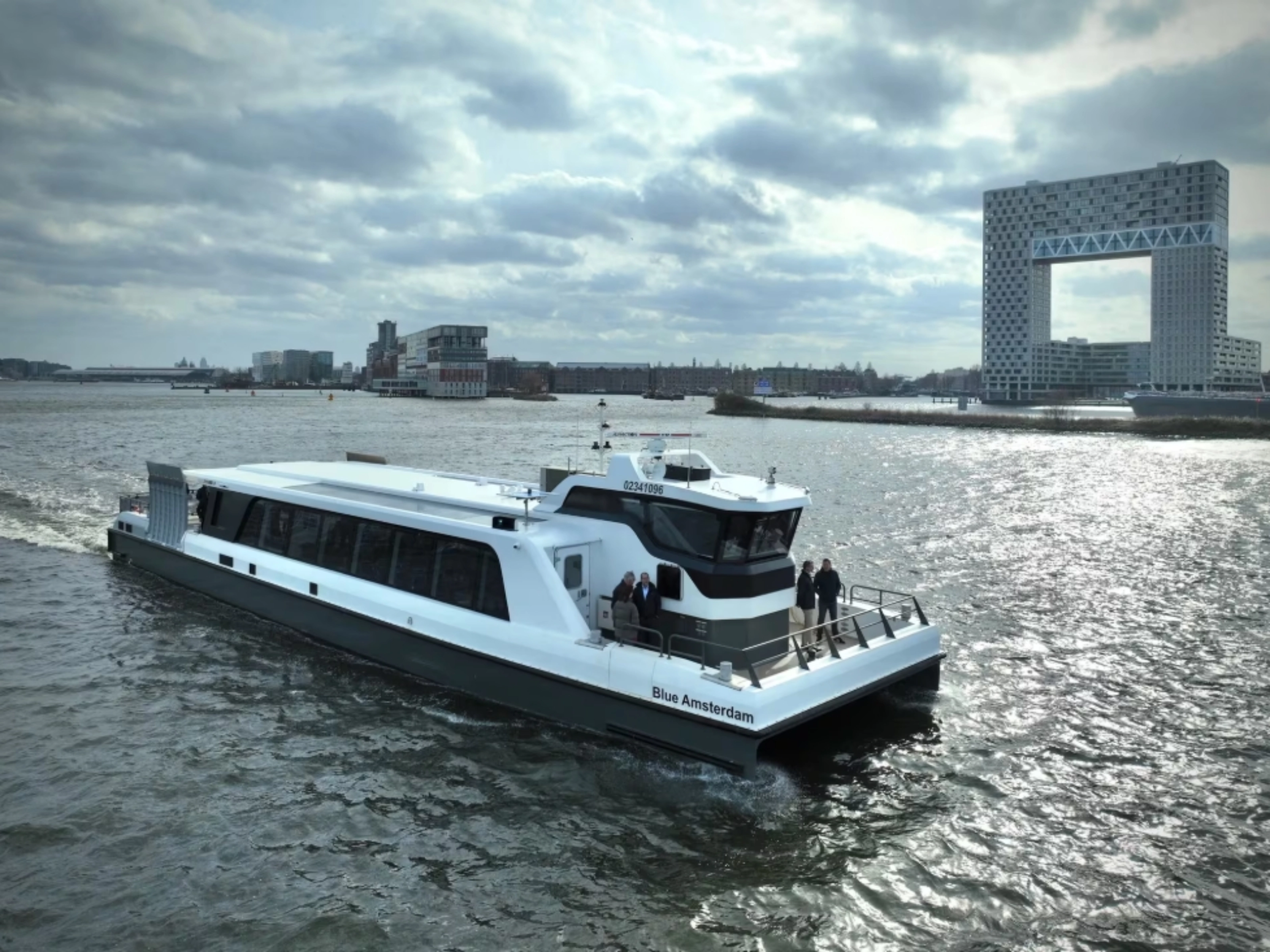 White passenger ferry on a river with modern city buildings in background