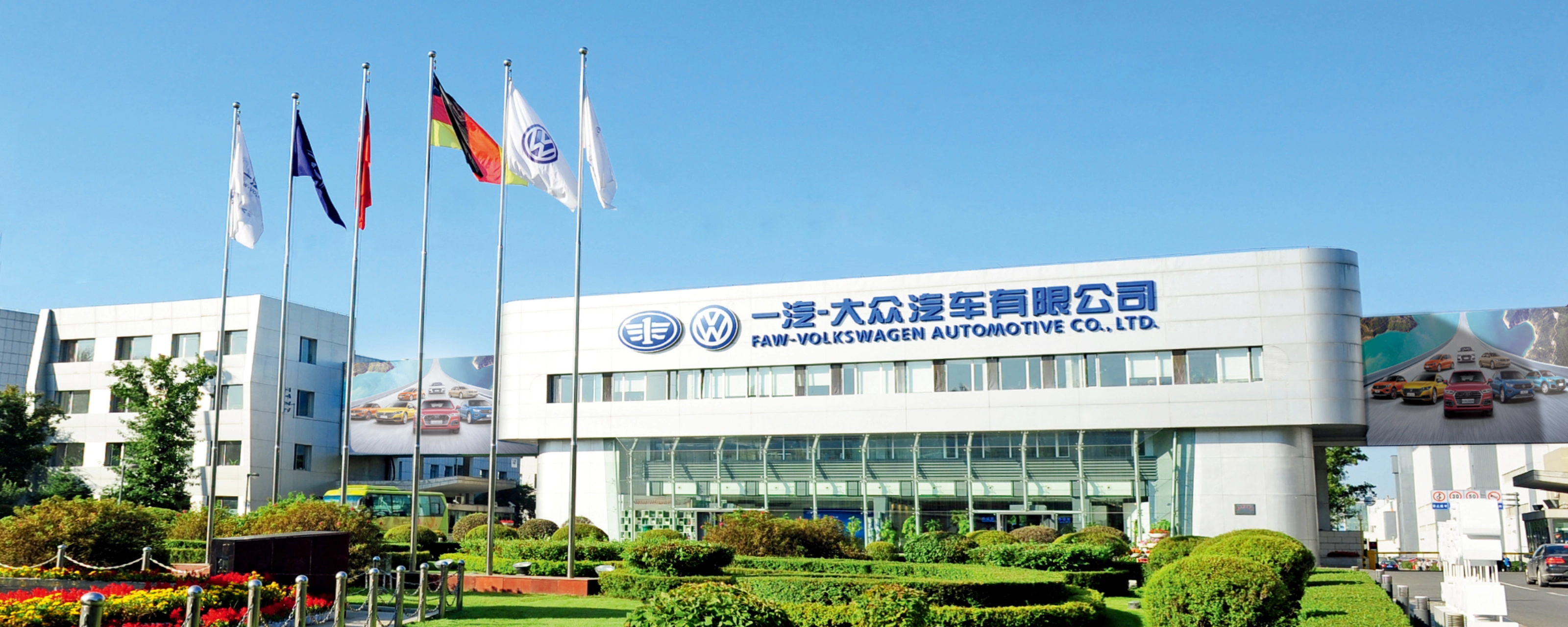 Haupteingang der FAW-Volkswagen Automotive Company mit Fahnen und Firmenschriftzug.
