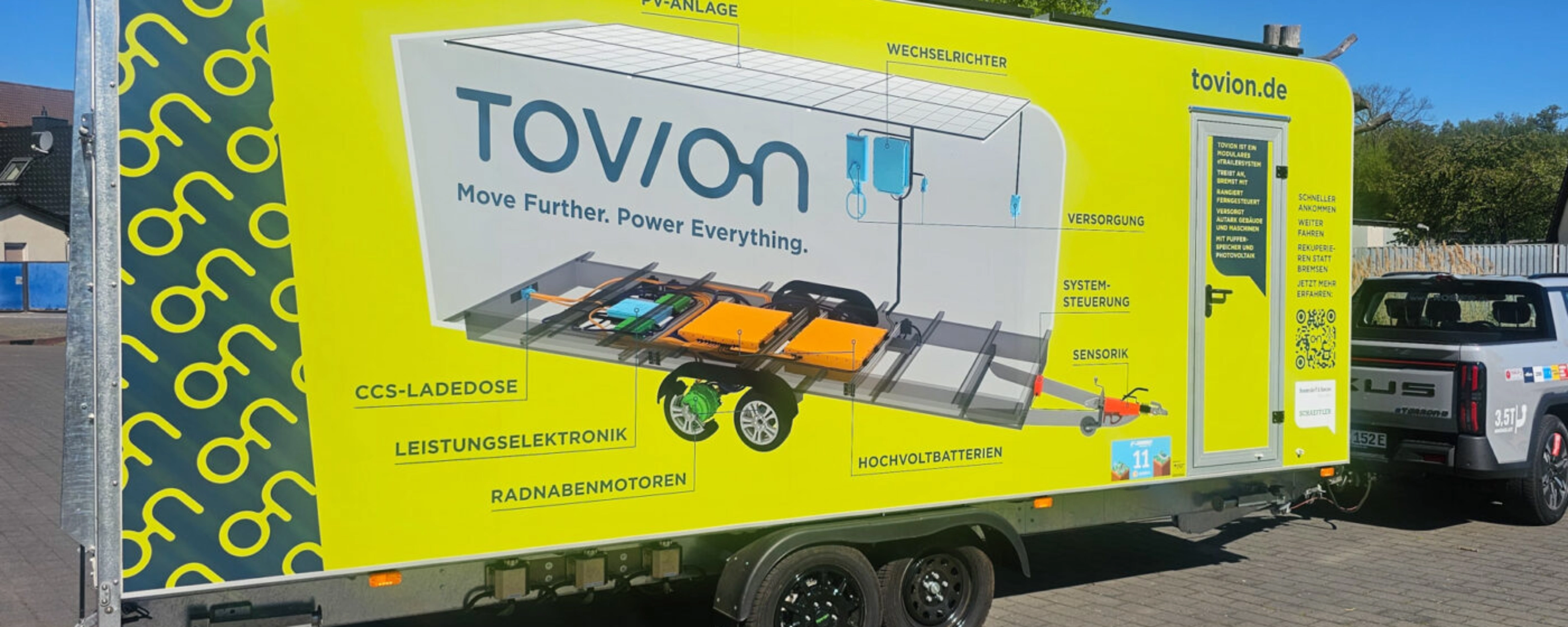 Yellow Tovion trailer with product graphic parked outdoors.
