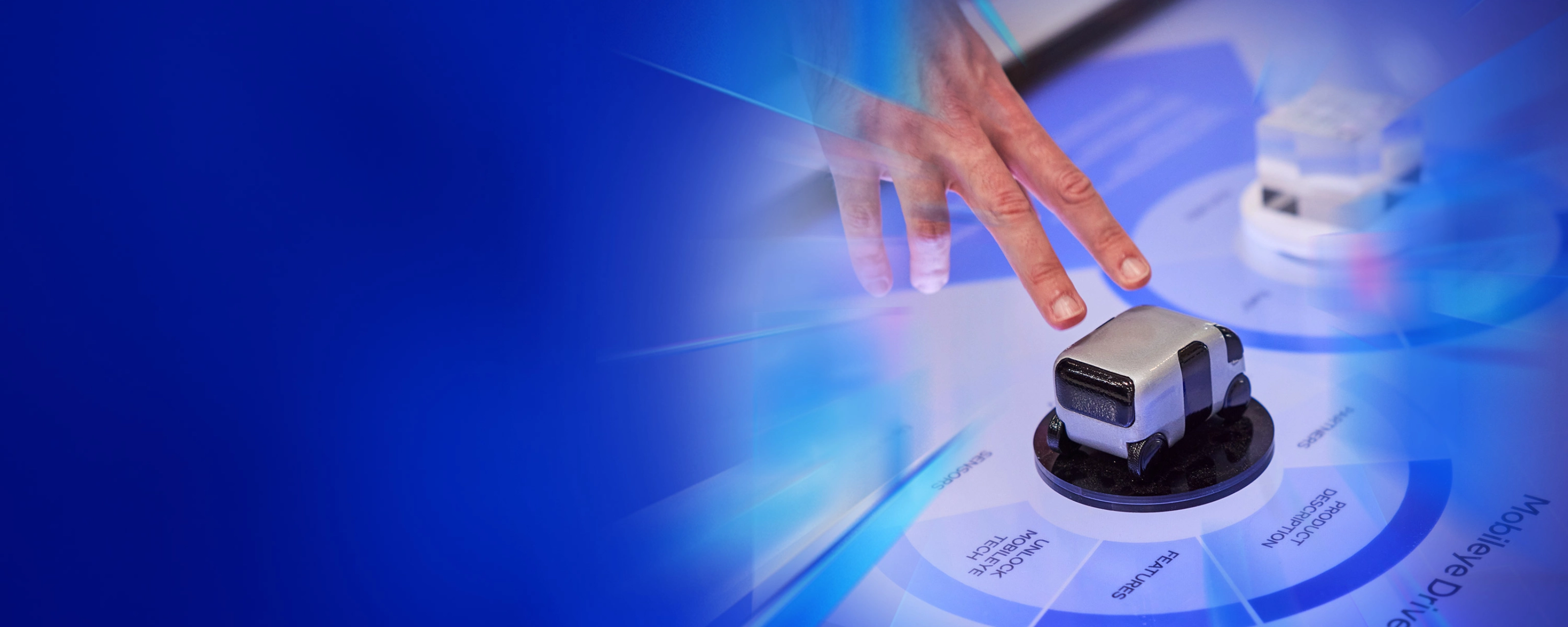 Eine Hand interagiert mit einem kleinen Fahrzeugmodell auf einer digitalen Fläche beim IAA Summit.