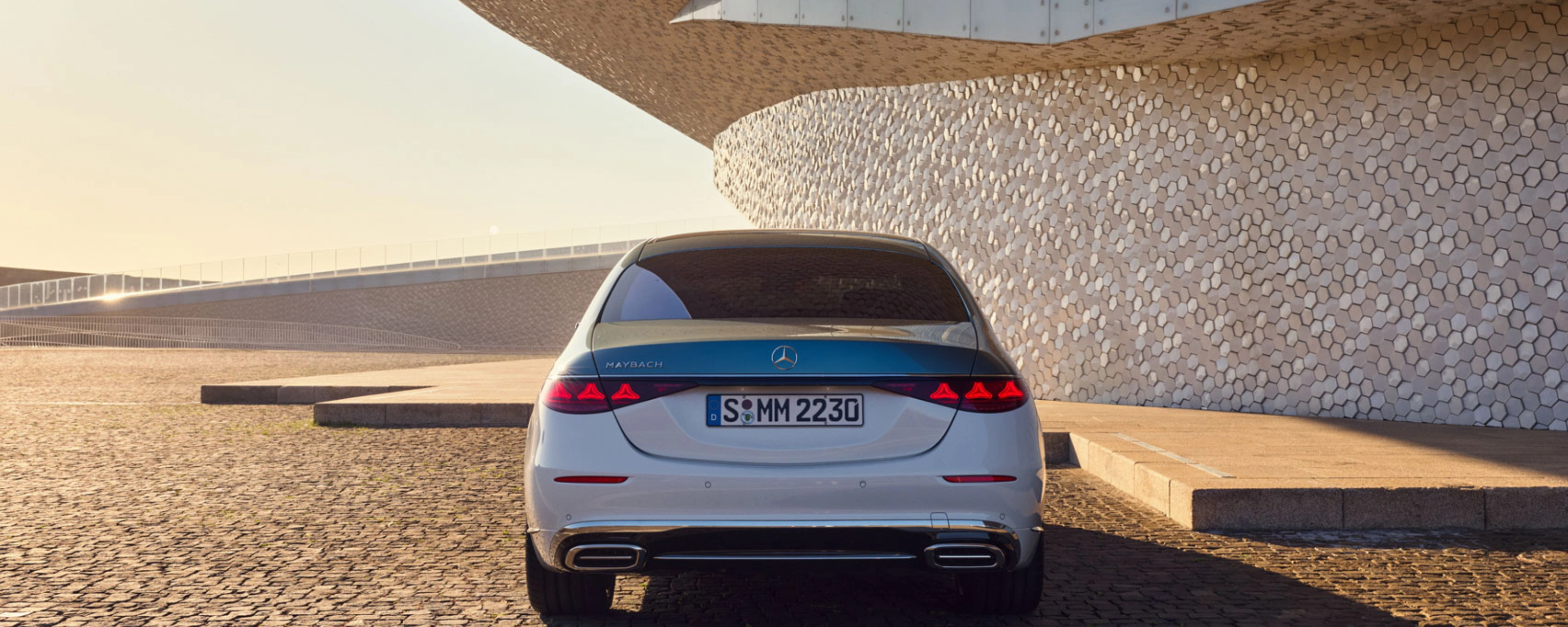 Rückansicht eines weißen Mercedes-Benz vor modernem Gebäude.