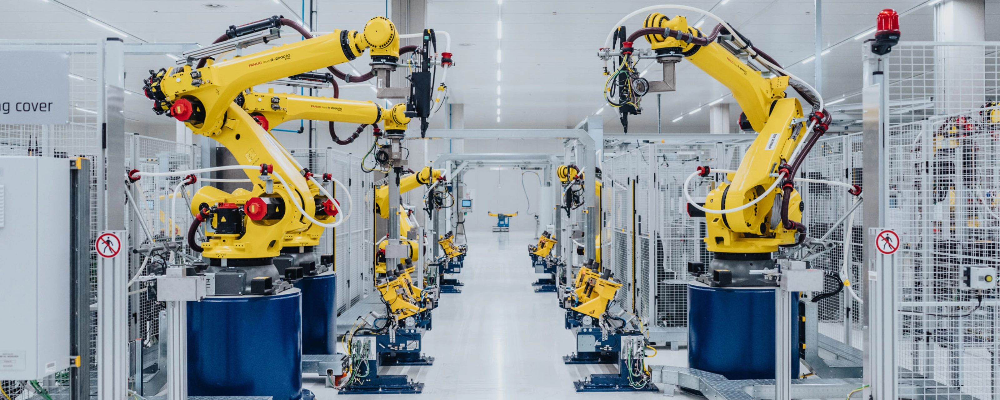 Automatisierte Fertigungslinie mit gelben Industrierobotern in einer Fabrikhalle.