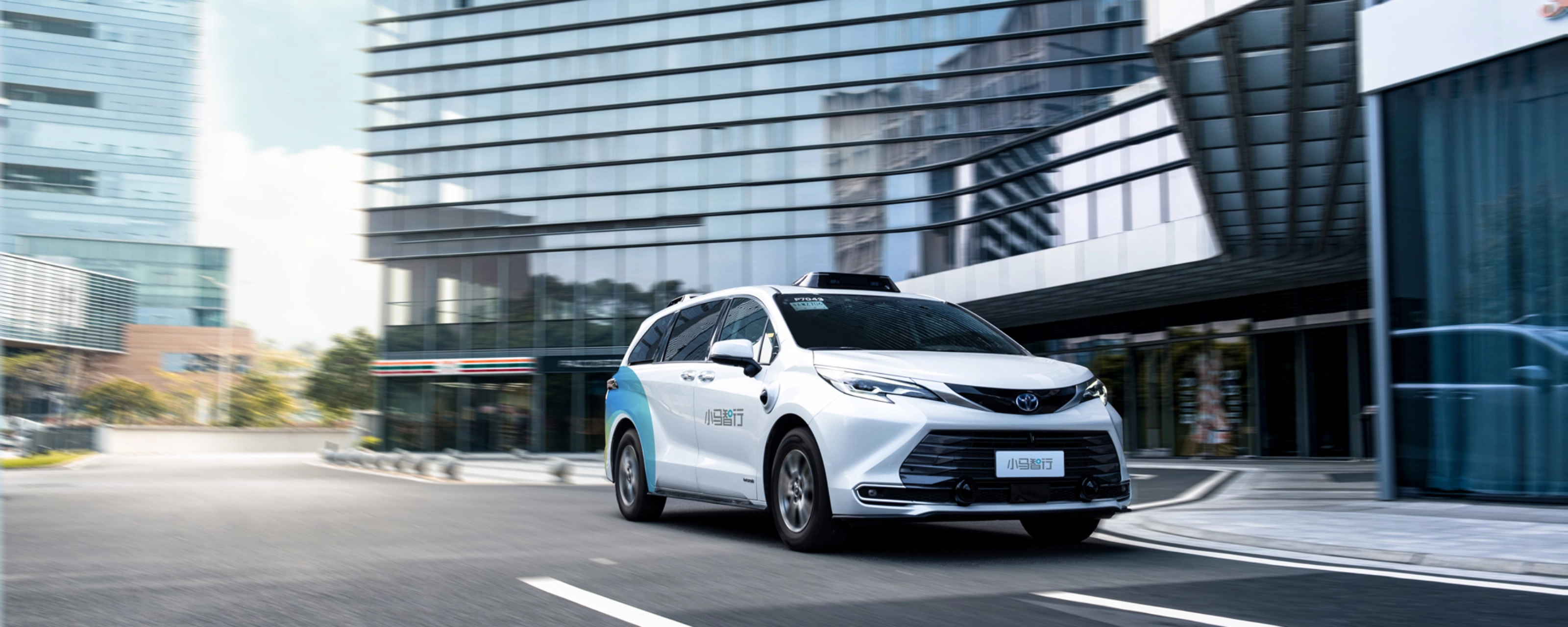 Autonomous minivan driving through modern city street.