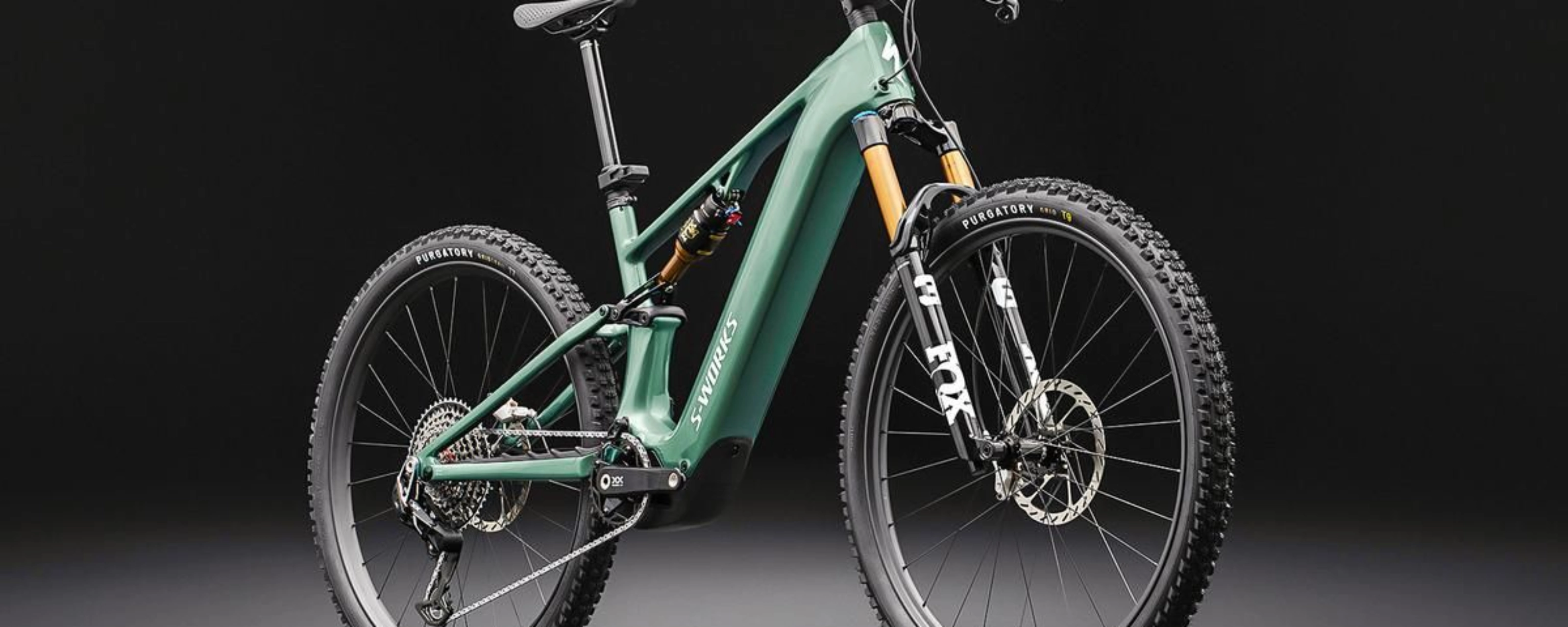 Green full-suspension mountain bike on a dark background.
