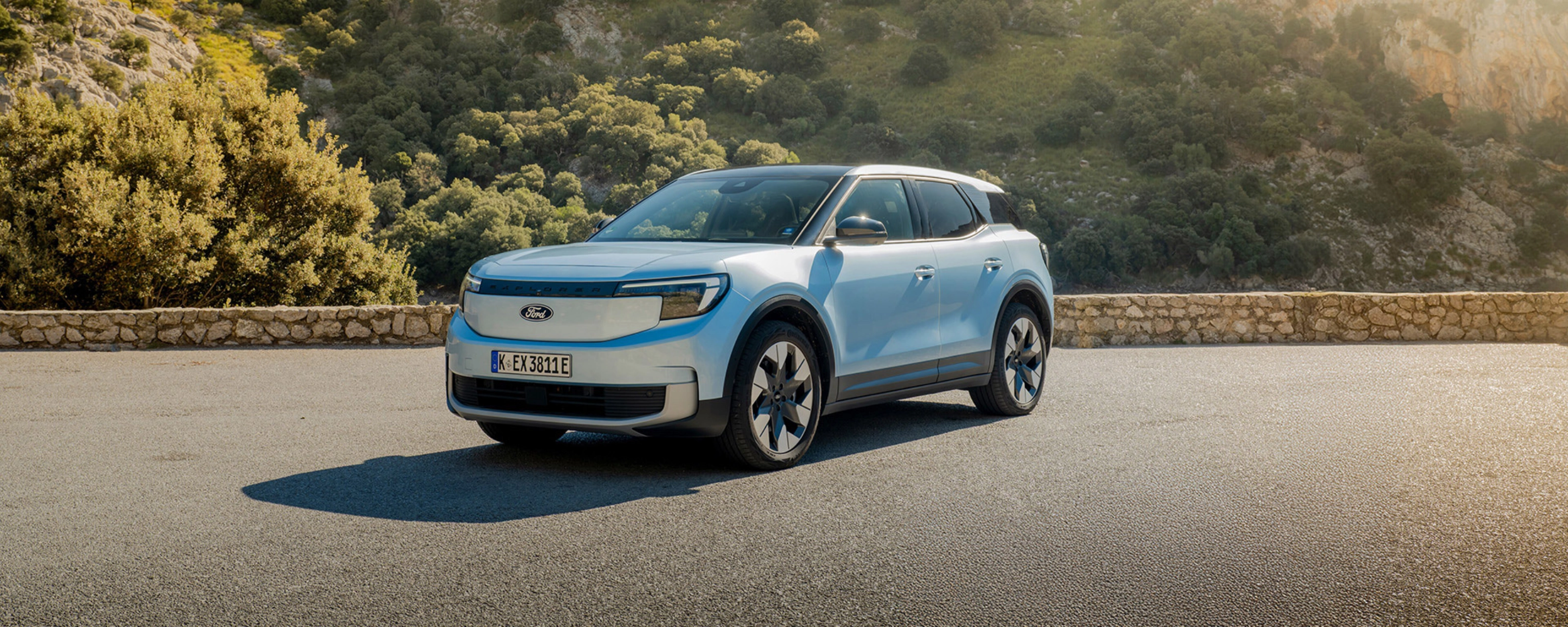 Ein hellblaues Elektro-SUV von Ford steht auf einer Bergstraße vor felsiger Hügellandschaft.