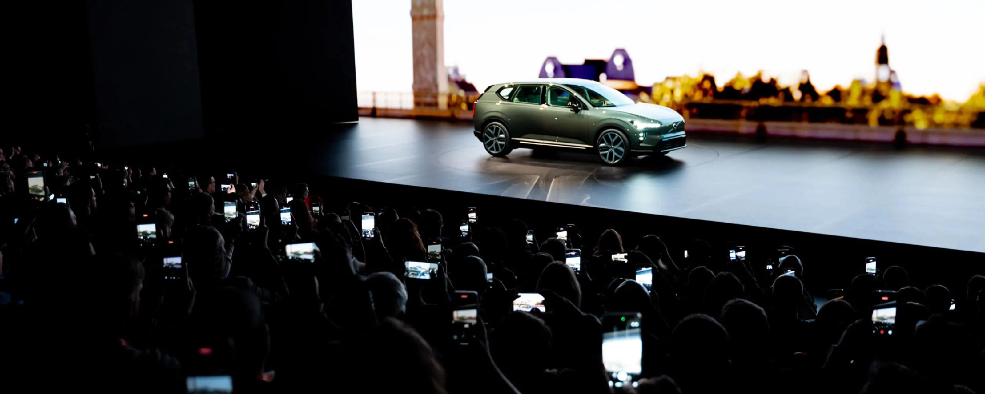 Elektrischer SUV wird auf einer Bühne präsentiert, das Publikum fotografiert mit Smartphones.