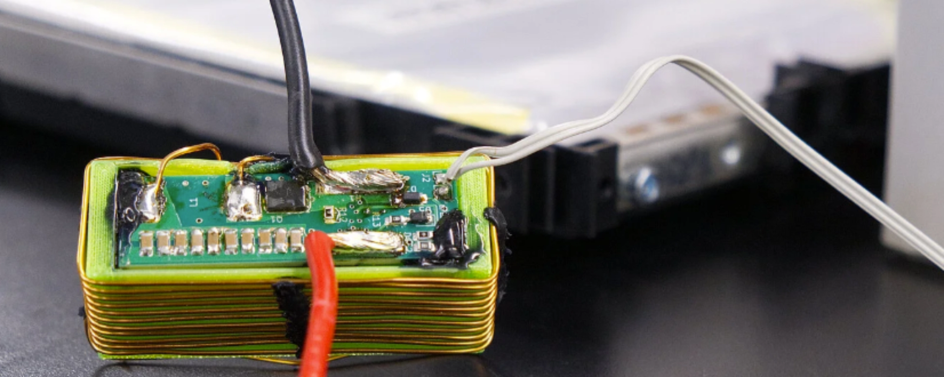 Nahaufnahme eines elektronischen Batteriemoduls mit angeschlossenen Kabeln auf einem Labortisch.