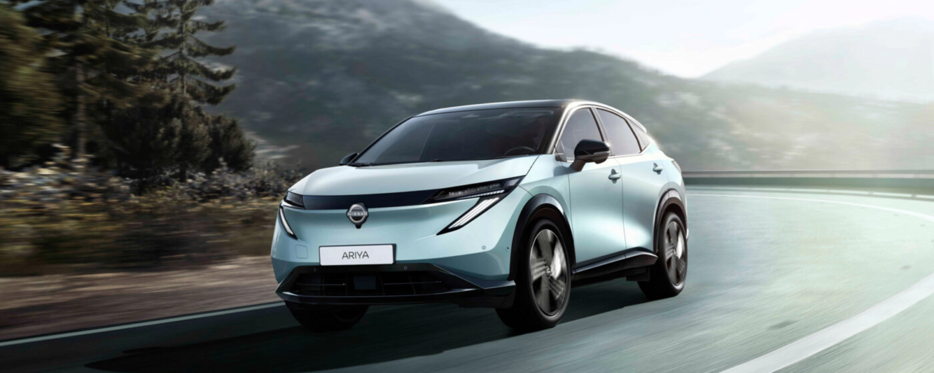 Nissan Ariya electric SUV driving on a mountain road.
