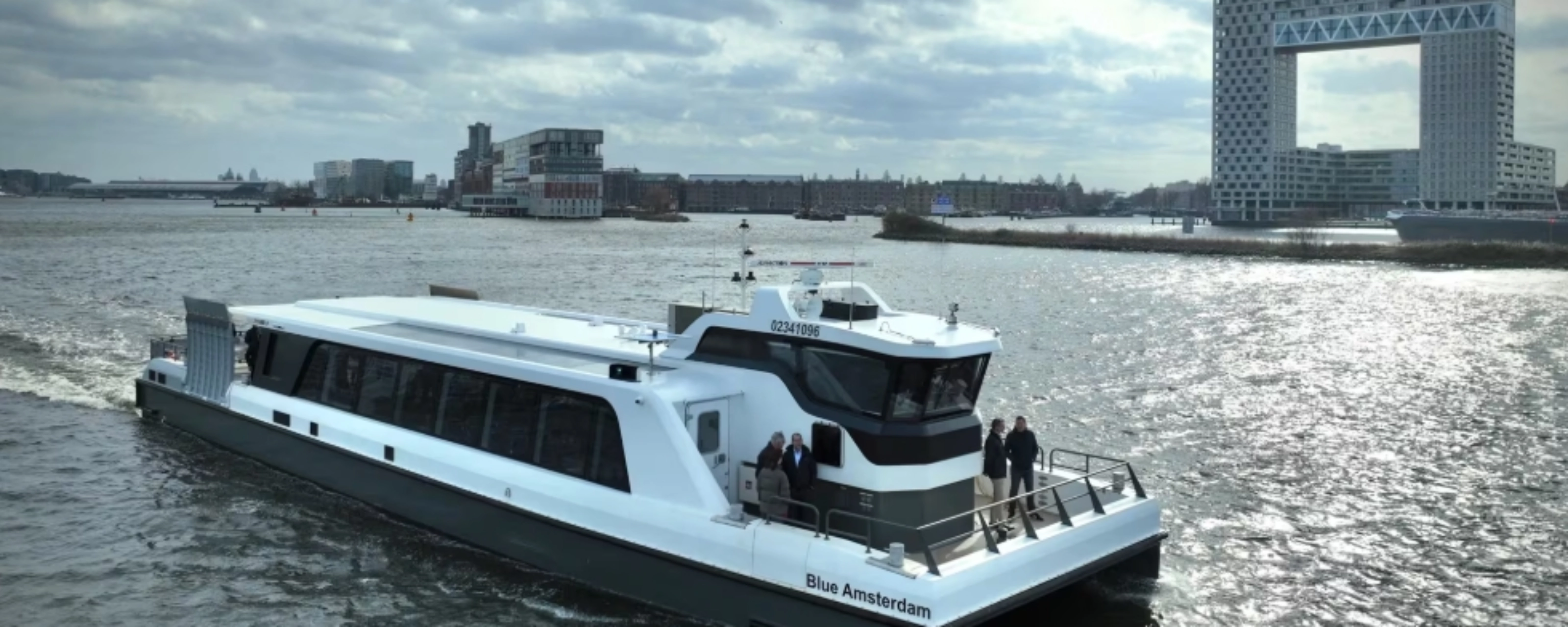 White passenger ferry on a river with modern city buildings in background