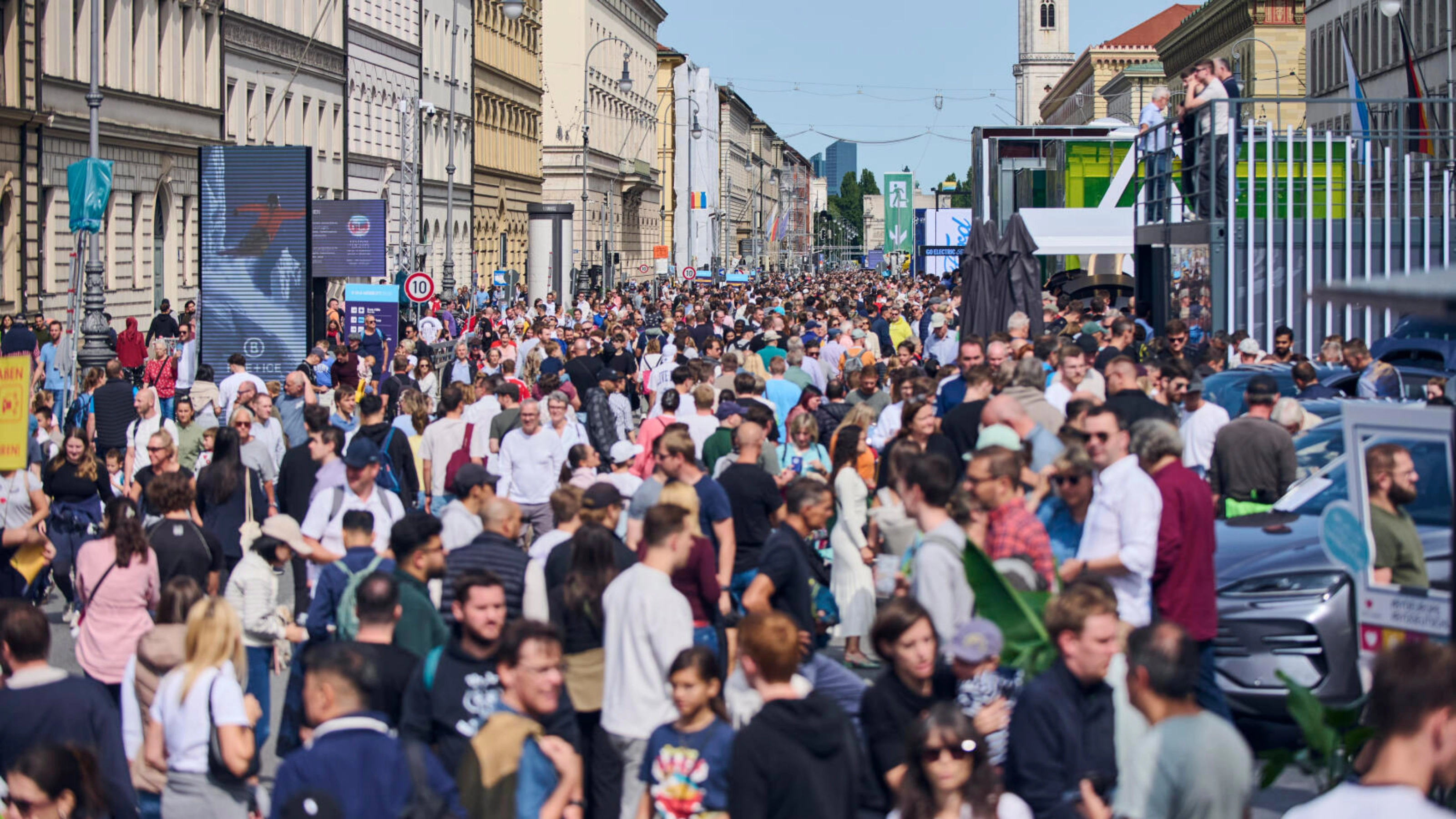 Crowded pedestrian street in a city center with many people walking between historic buildings.