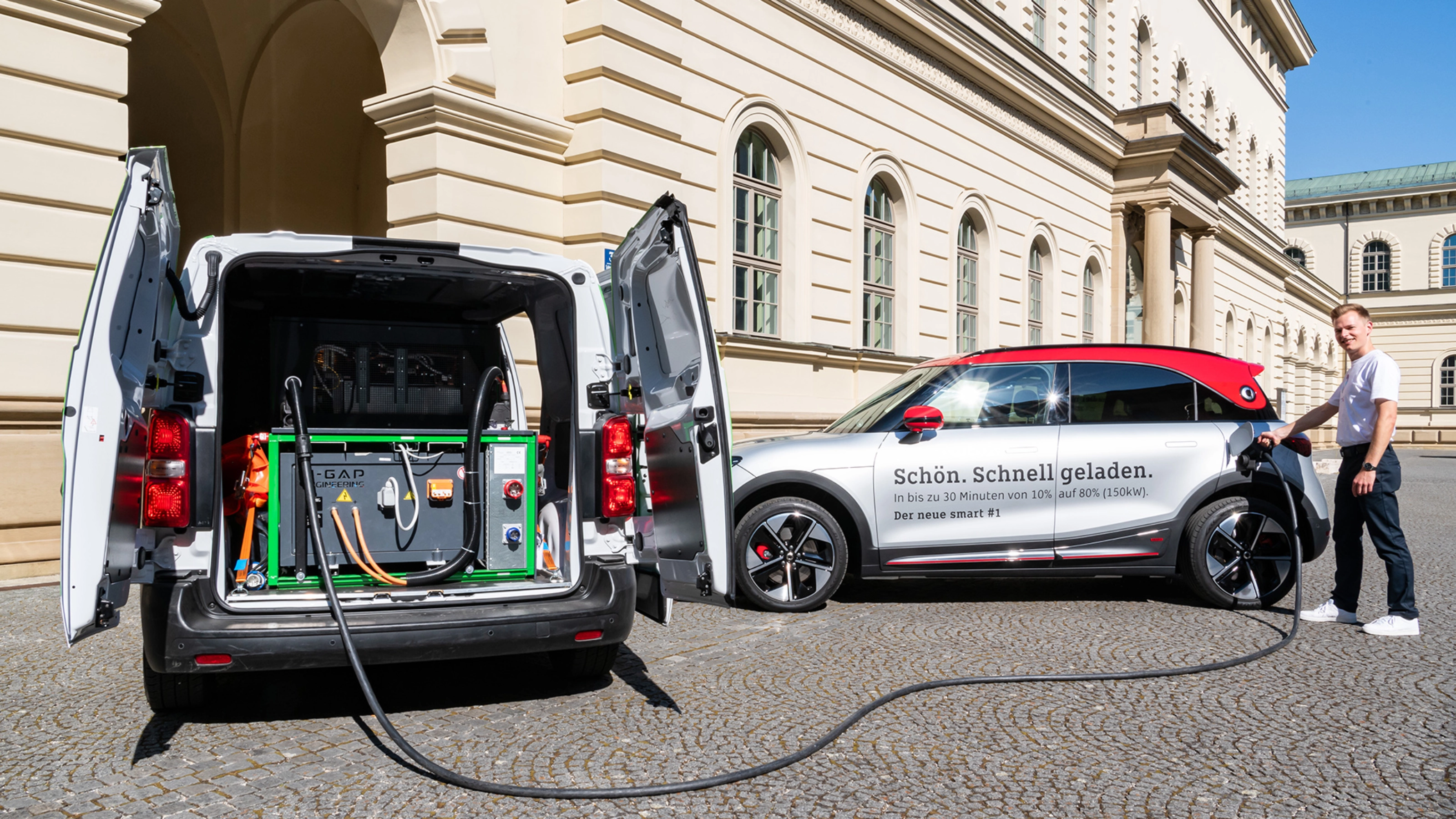 A man charges an electric car using mobile charging equipment from a van.