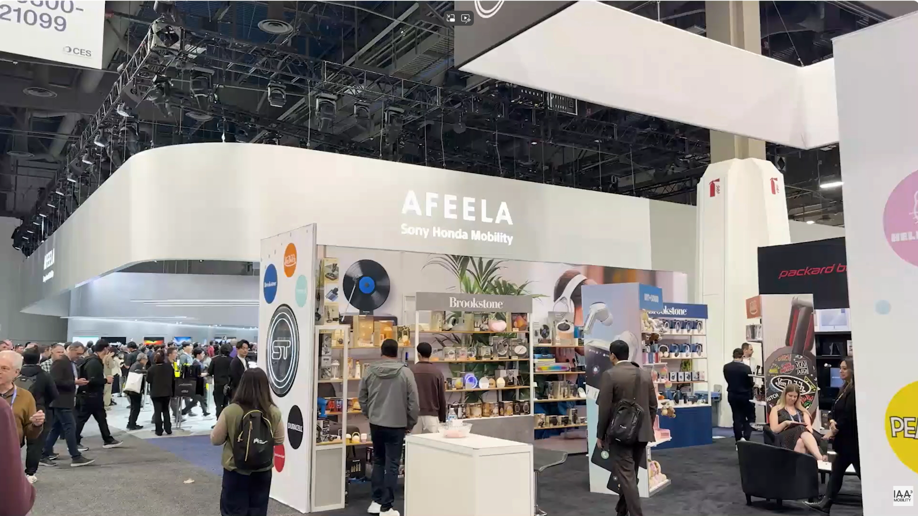 Exhibition booth of AFEELA by Sony Honda Mobility with people walking and browsing products.