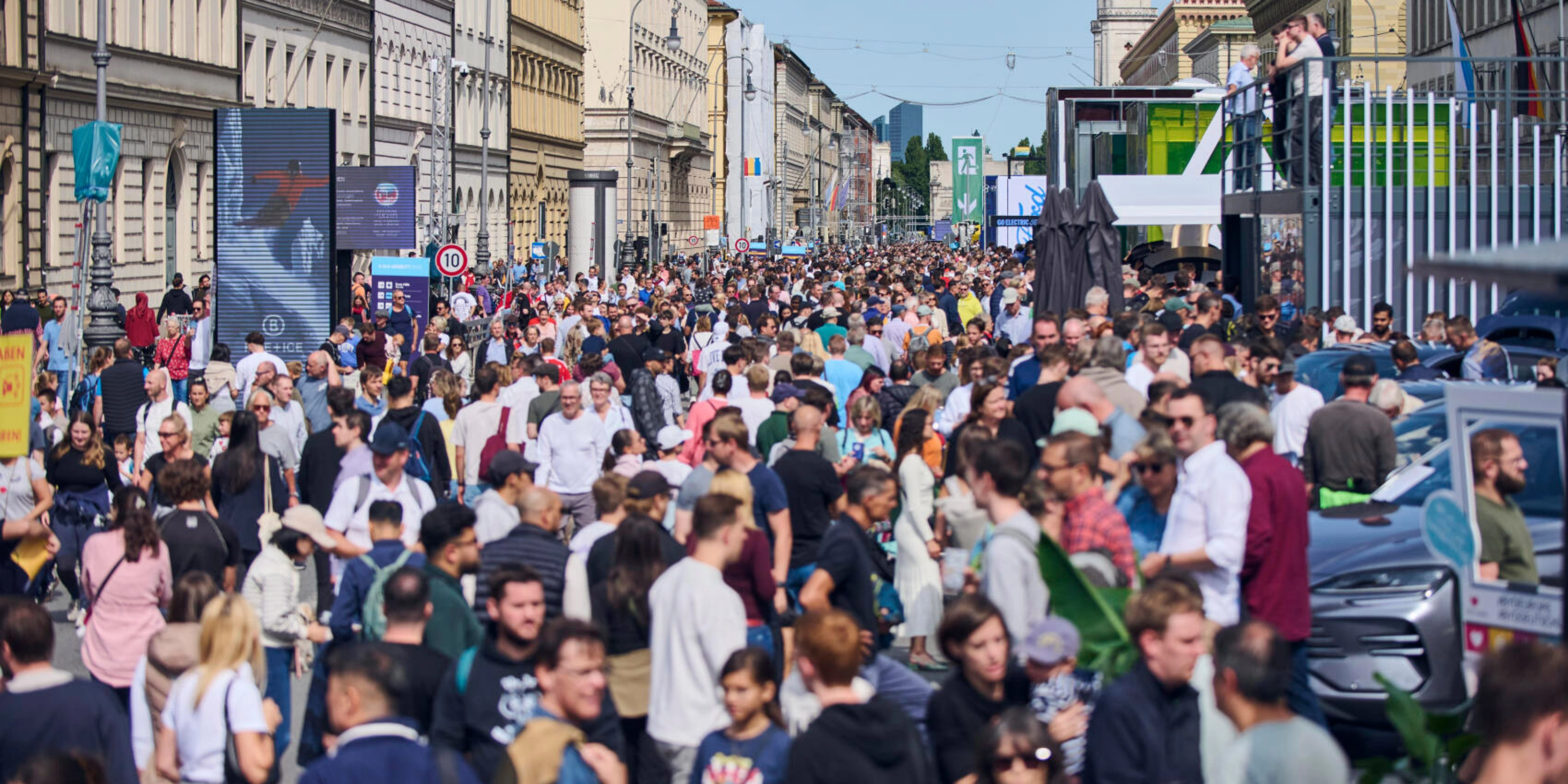 Crowded pedestrian street in a city center with many people walking between historic buildings.