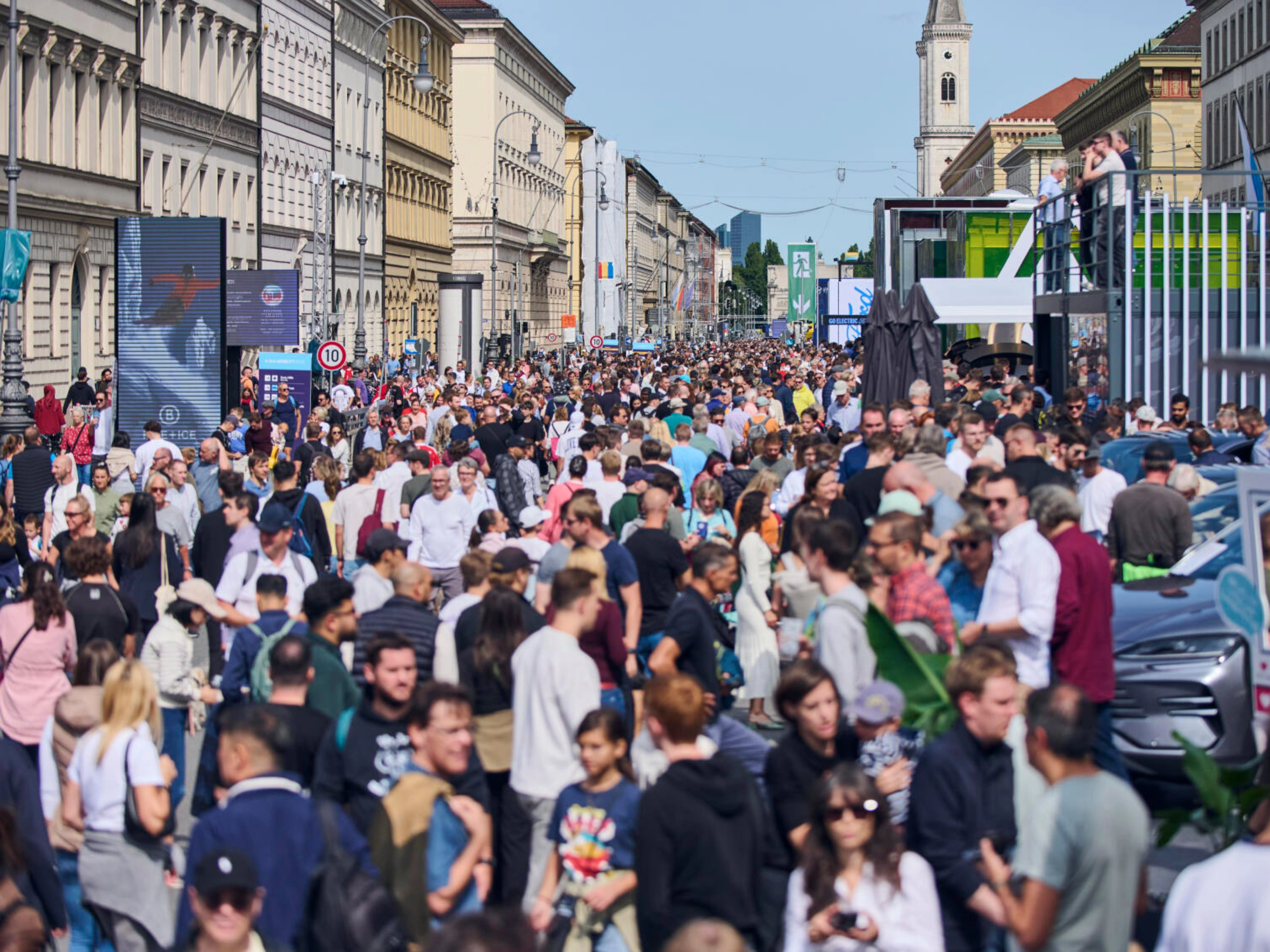 Crowded pedestrian street in a city center with many people walking between historic buildings.