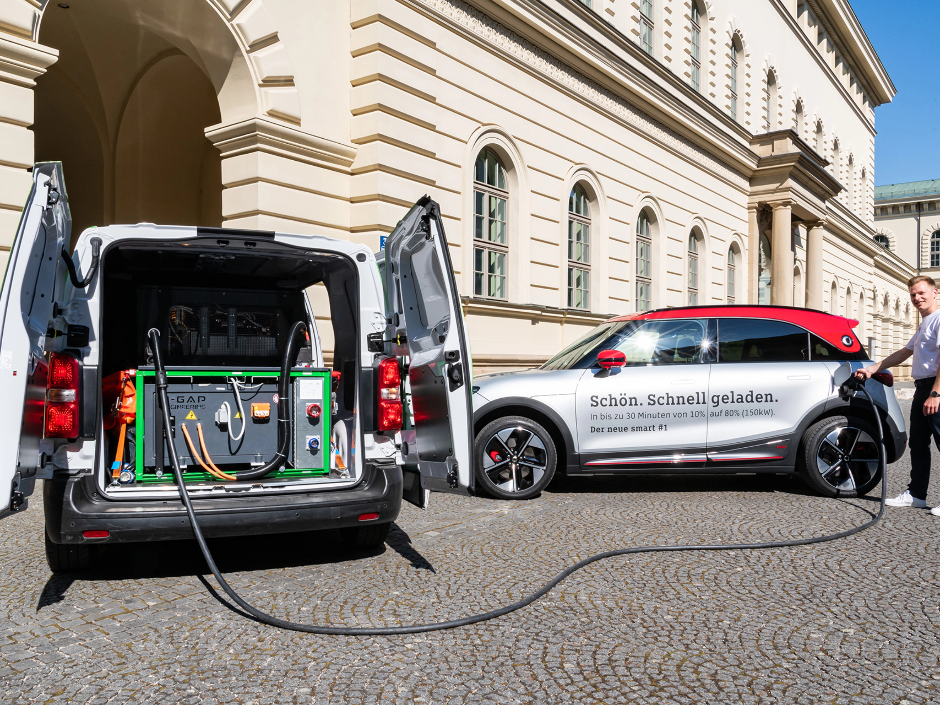 A man charges an electric car using mobile charging equipment from a van.