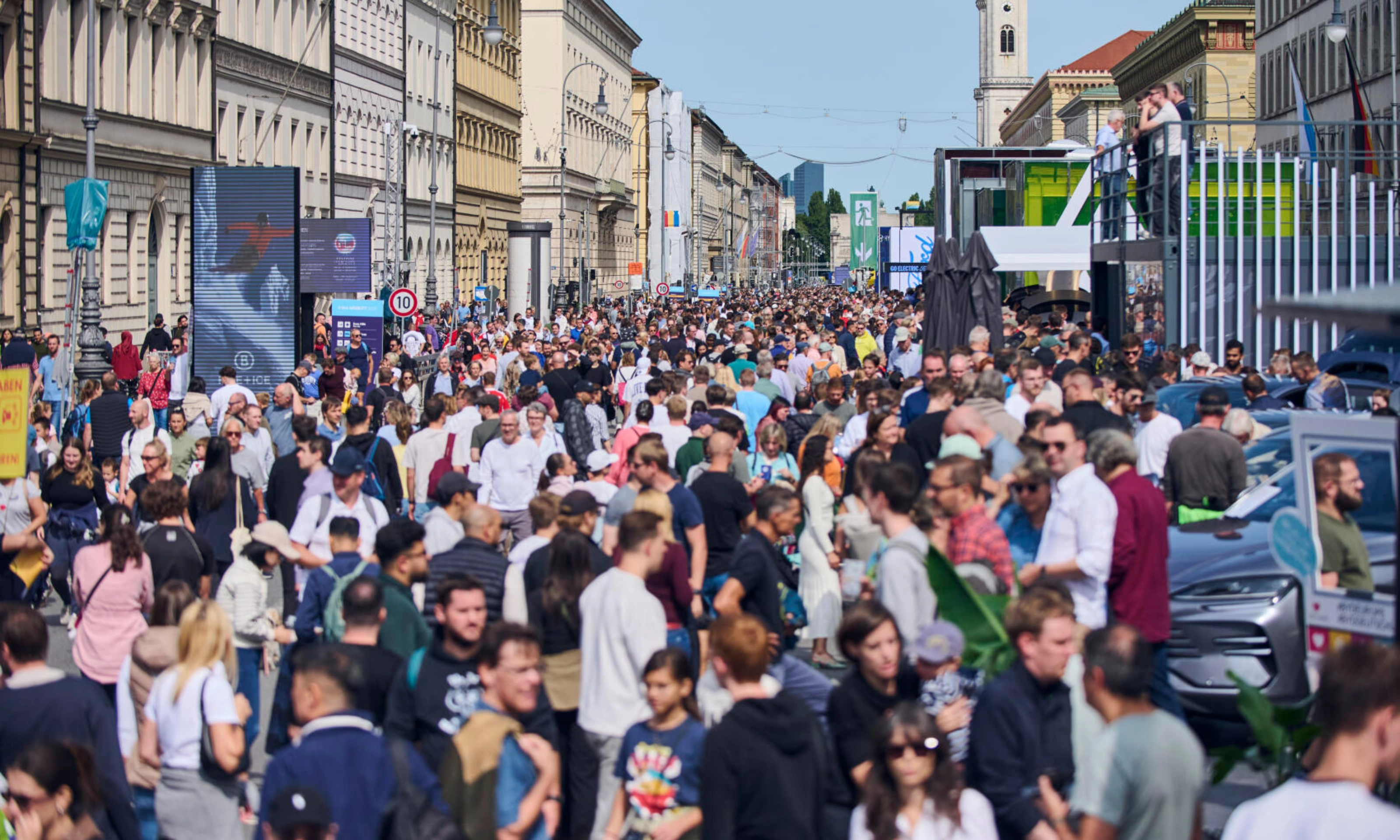Crowded pedestrian street in a city center with many people walking between historic buildings.