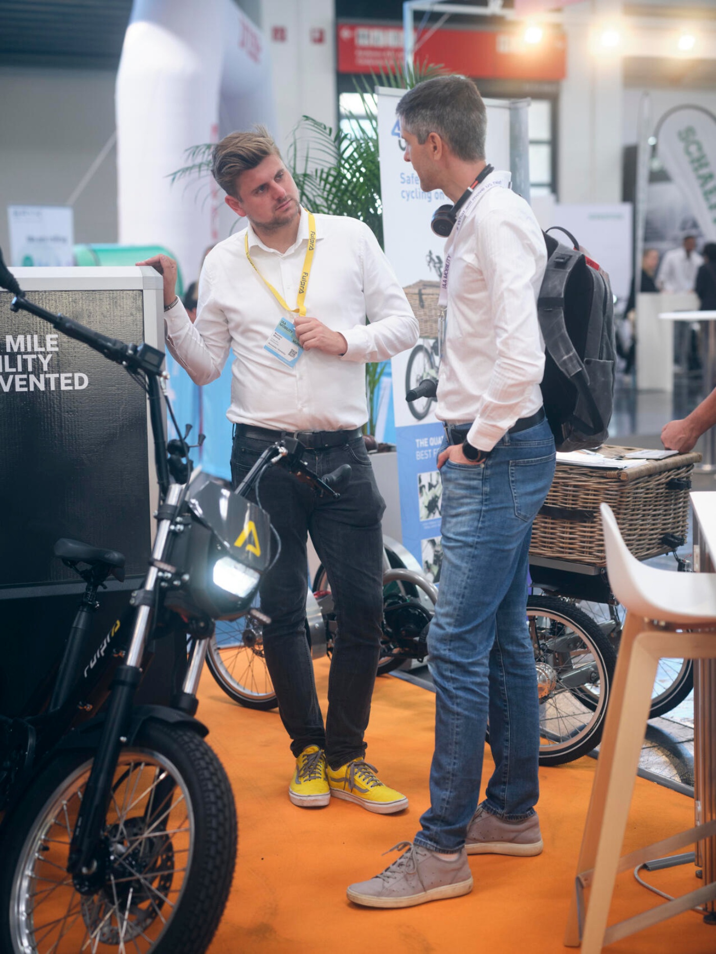 Zwei Männer sprechen vor einem Elektro-Lastenrad an einem Stand auf einer Mobilitätsmesse.