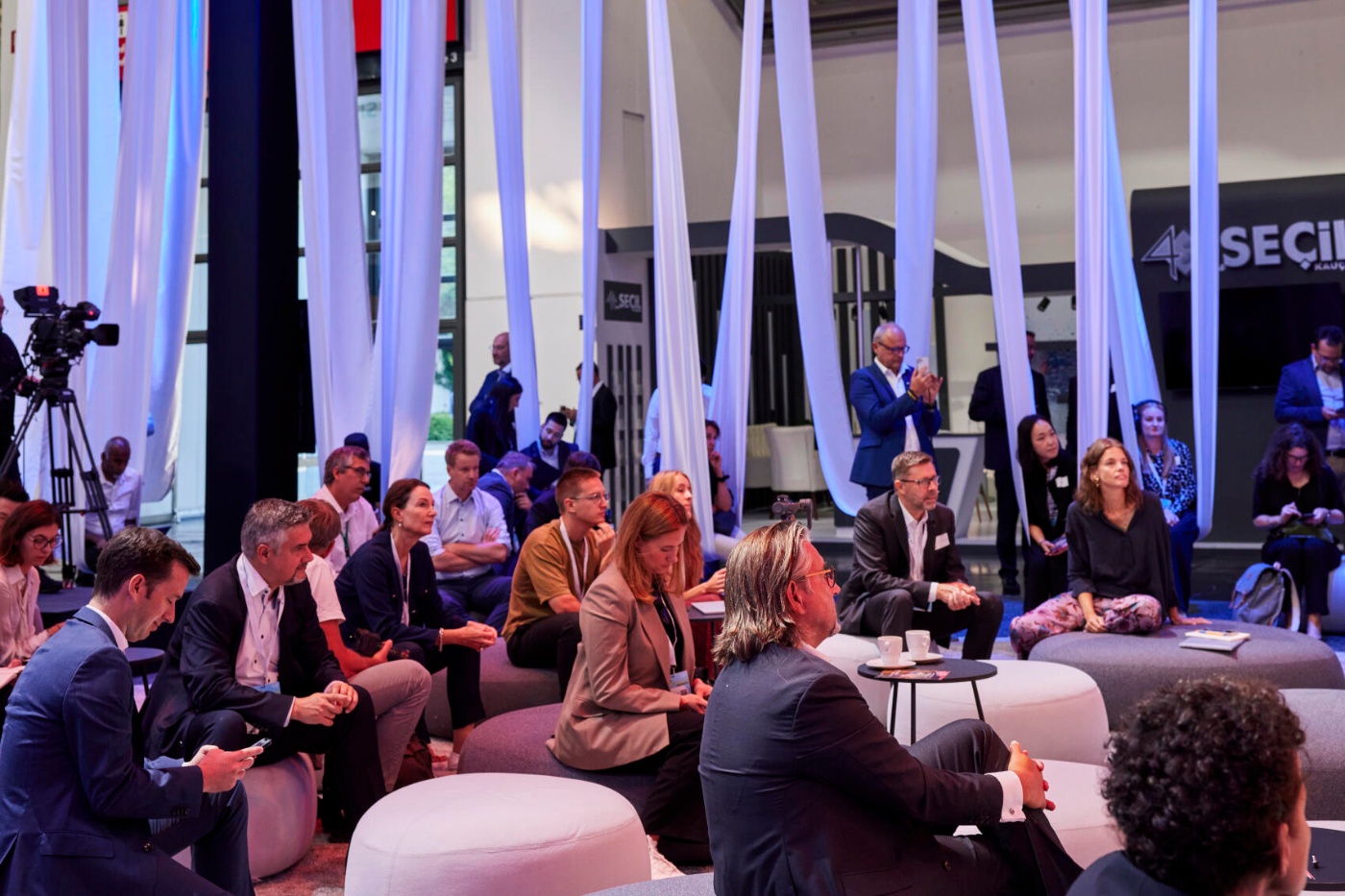 Teilnehmende sitzen auf Hockern und Kissen bei einer Diskussionsrunde auf der IAA MOBILITY 2023.