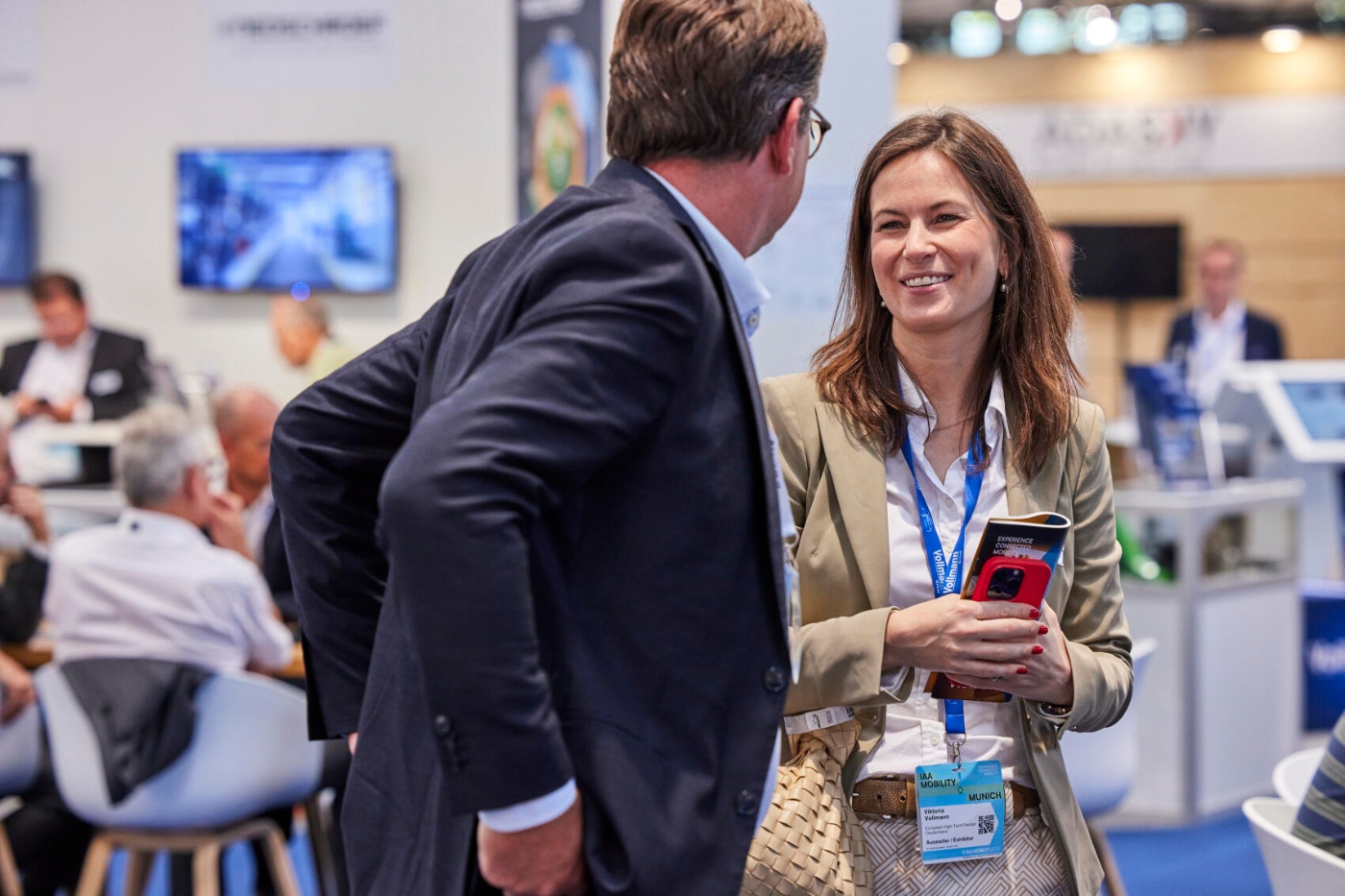 A woman and a man talk and smile during a networking moment at a mobility trade fair.