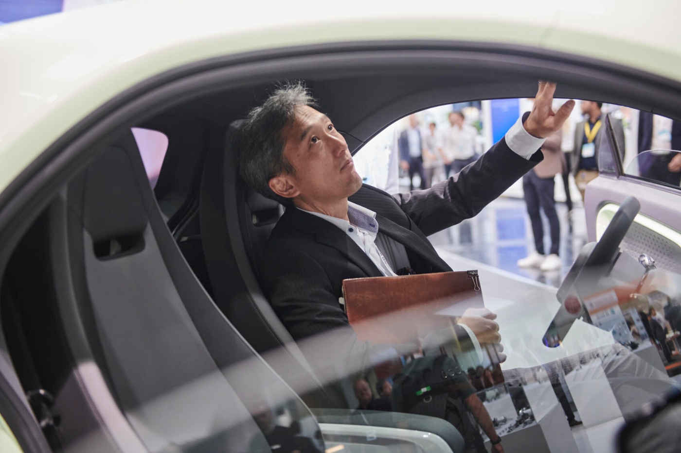 A man sits inside a concept car, reaching up while examining the vehicle’s interior.