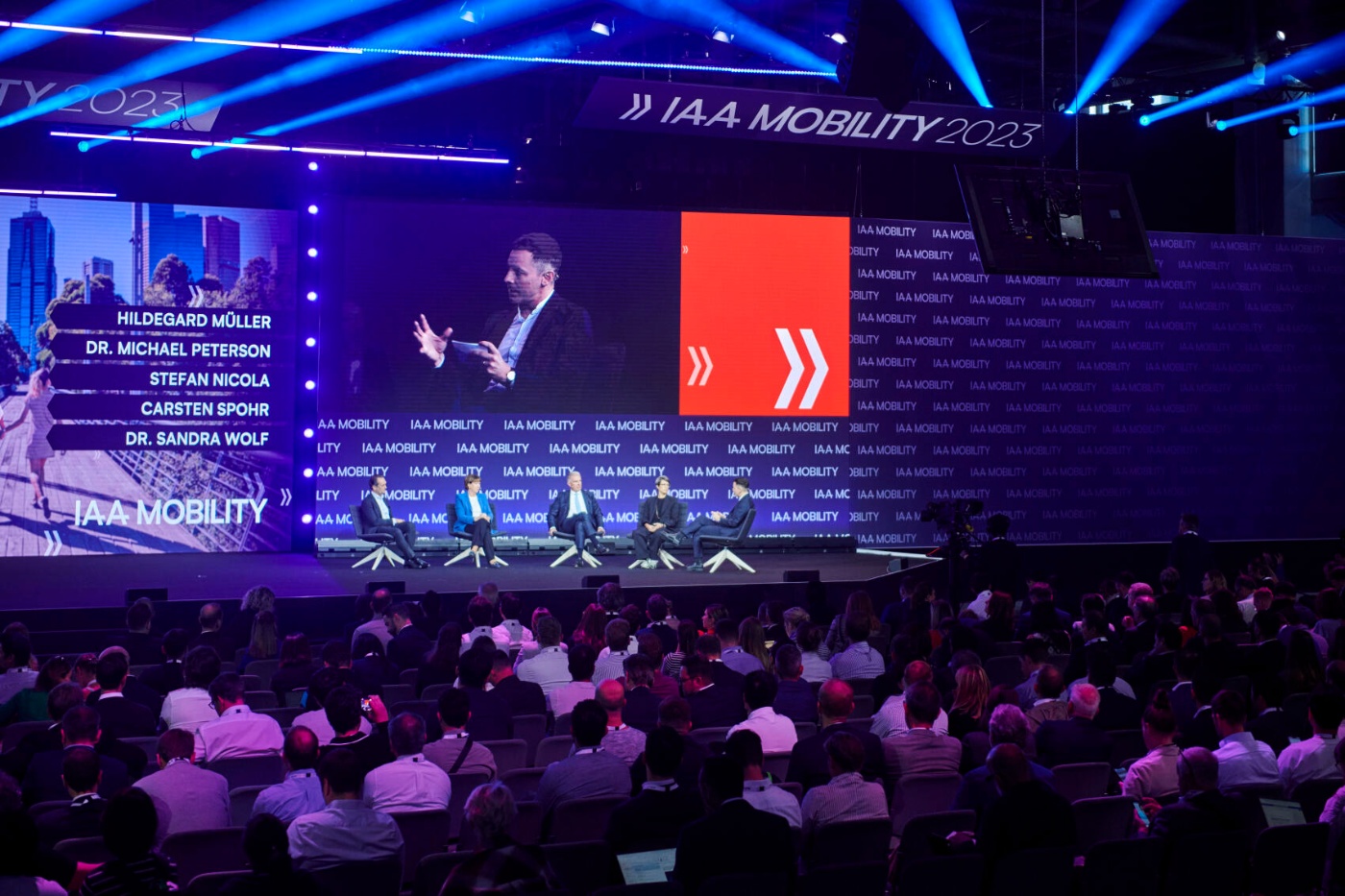 Panel discussion with audience at IAA Mobility 2023, large screens show speakers and topics.