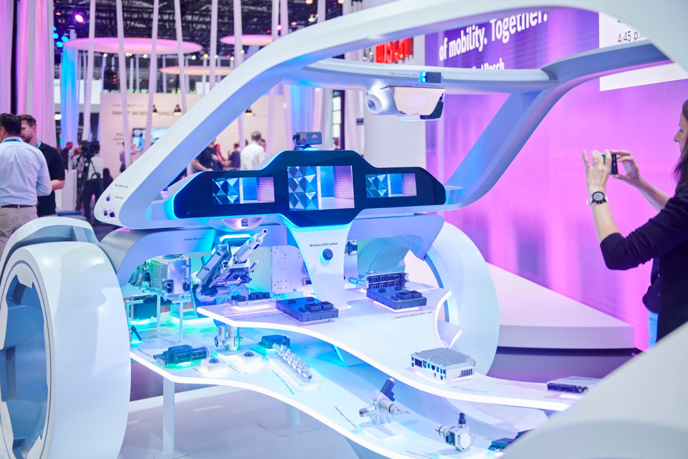 A futuristic vehicle interior model with exposed electronic components is displayed at a booth.