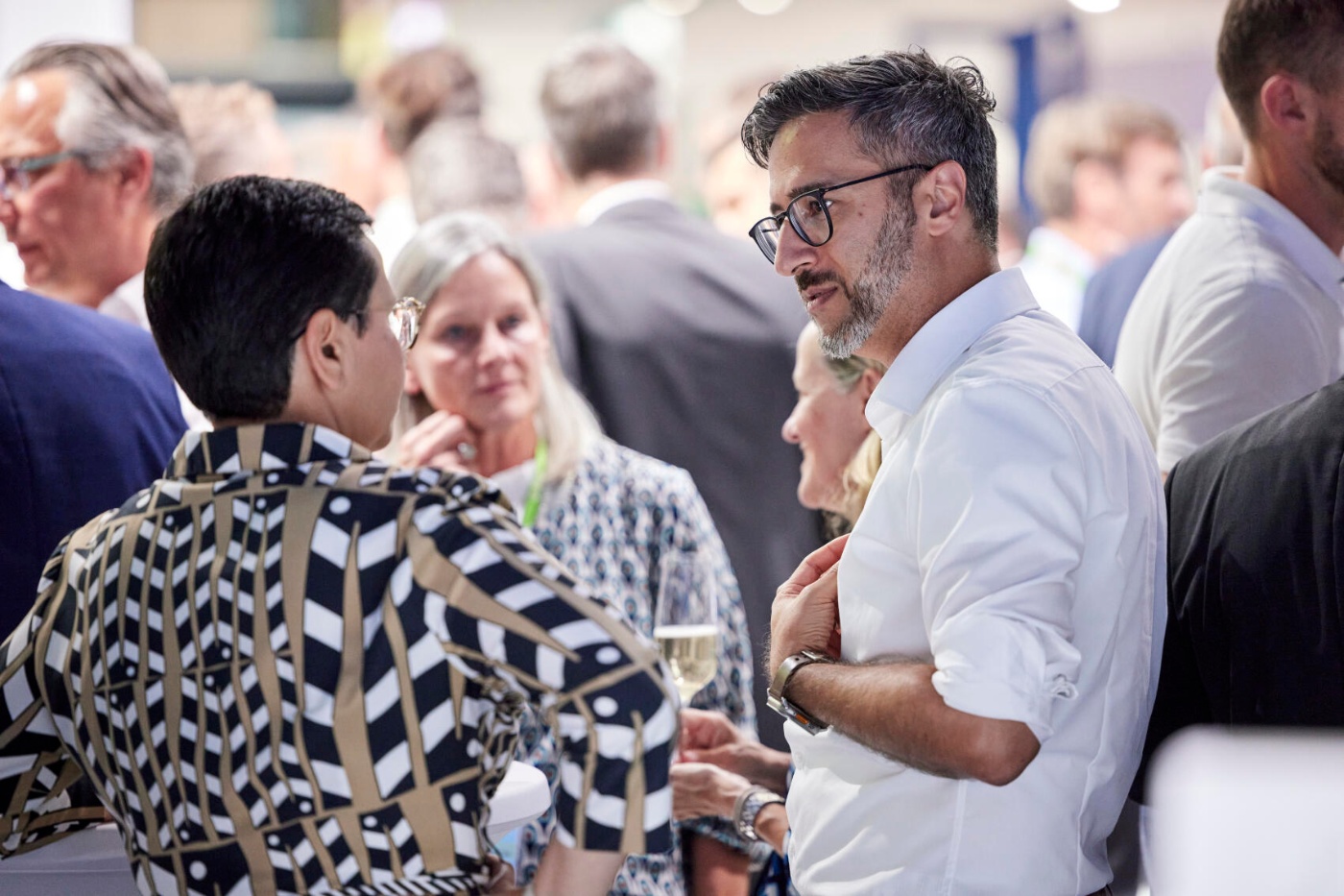 People in conversation at a trade fair networking event, surrounded by a busy crowd.
