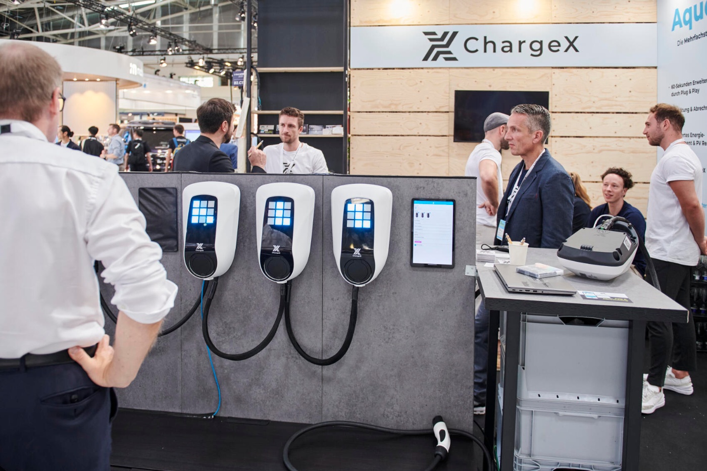 Besucher betrachten Ladelösungen für E-Fahrzeuge am Stand von ChargeX auf einer Messe.