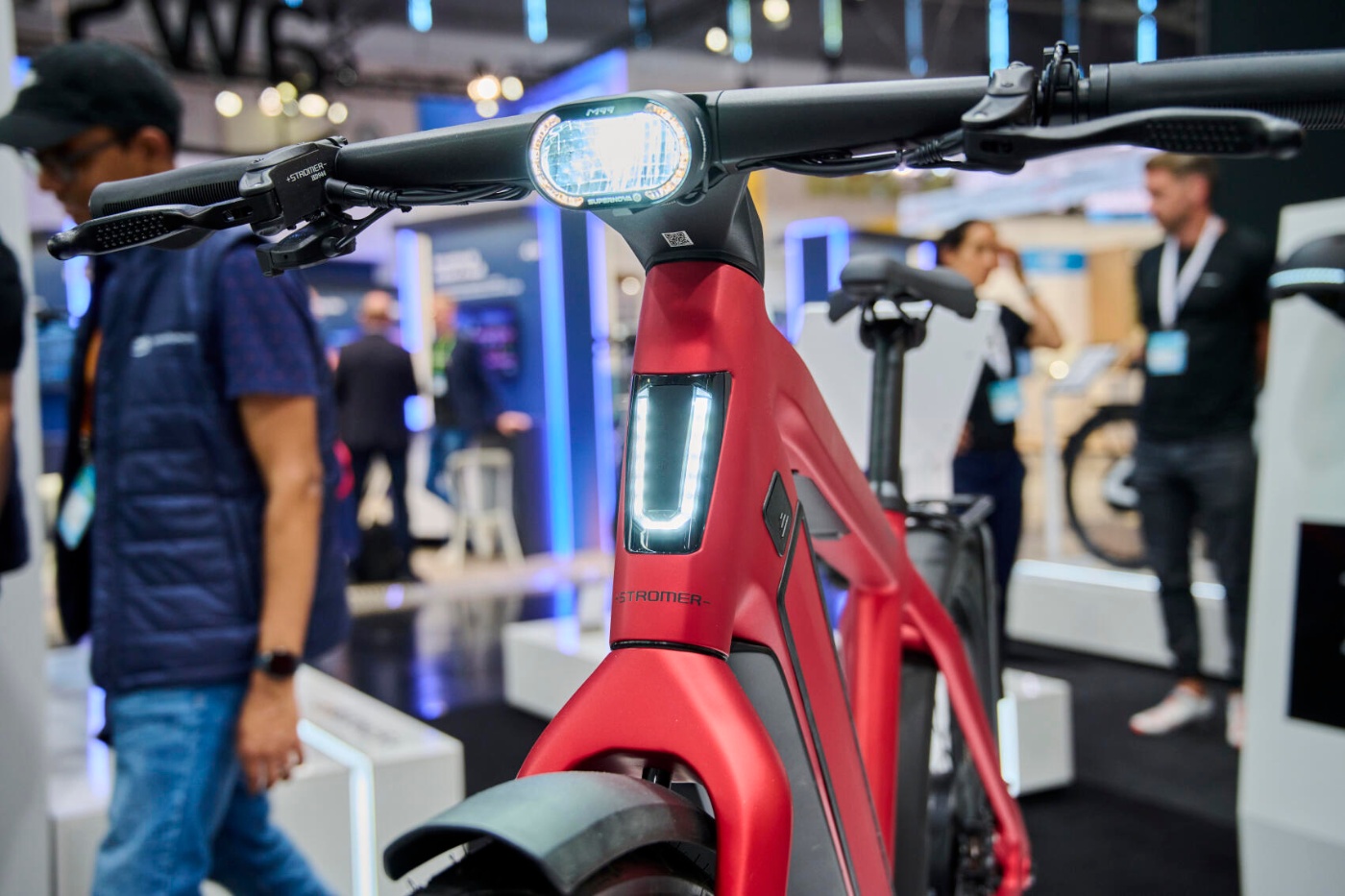 Rotes E-Bike mit integrierter Frontleuchte auf einem Messestand für Mobilität ausgestellt.