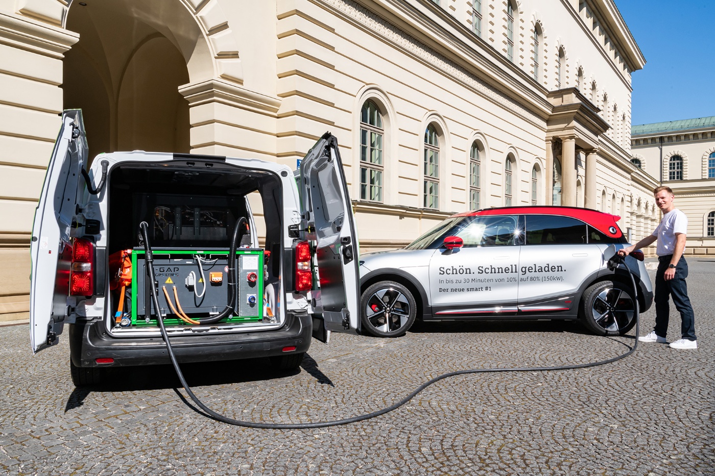 Ein Mann lädt ein Elektroauto mit mobiler Ladeausrüstung aus einem Transporter auf.