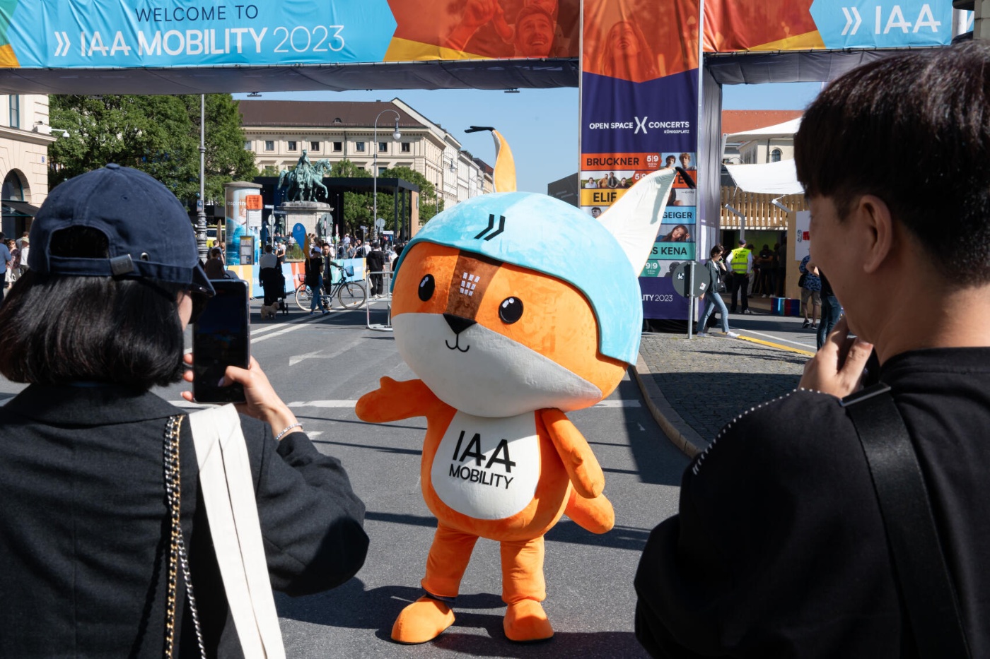 People take photos of the IAA Mobility 2023 fox mascot standing in the street.