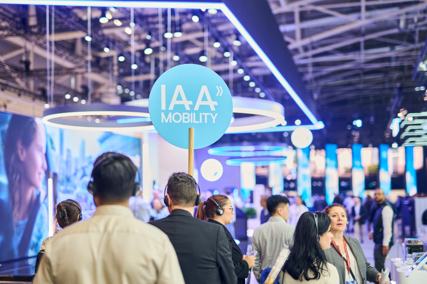 Guided Tour auf der IAA MOBILITY 2025 mit einem Tour Guide, der ein IAA MOBILITY Schild hochhält. Hinter ihm die Gruppe an Teilnehmern der Tour, die ihm folgt.