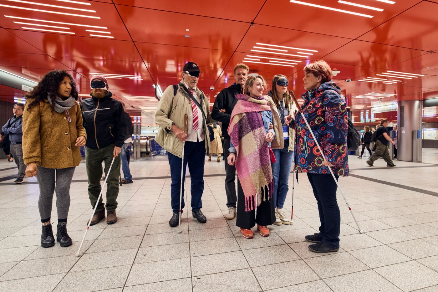Eine Gruppe mit Langstöcken und Augenbinden steht bei einer Aktion in einer U-Bahn-Station.