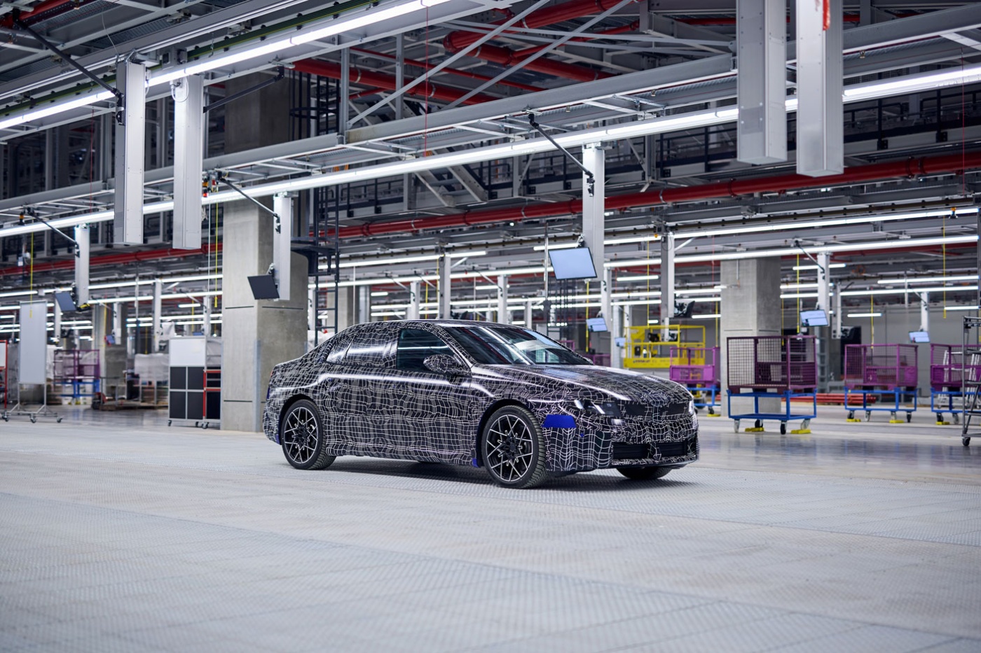 Eine getarnte Limousine steht in einer sauberen, weitläufigen Fahrzeugproduktionshalle.