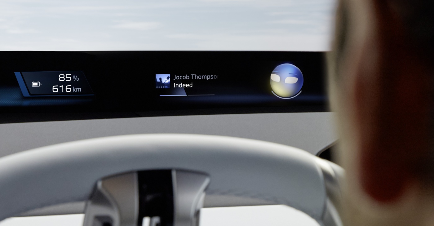 Close-up of a digital car dashboard showing battery level, range, music info, and an animated face.