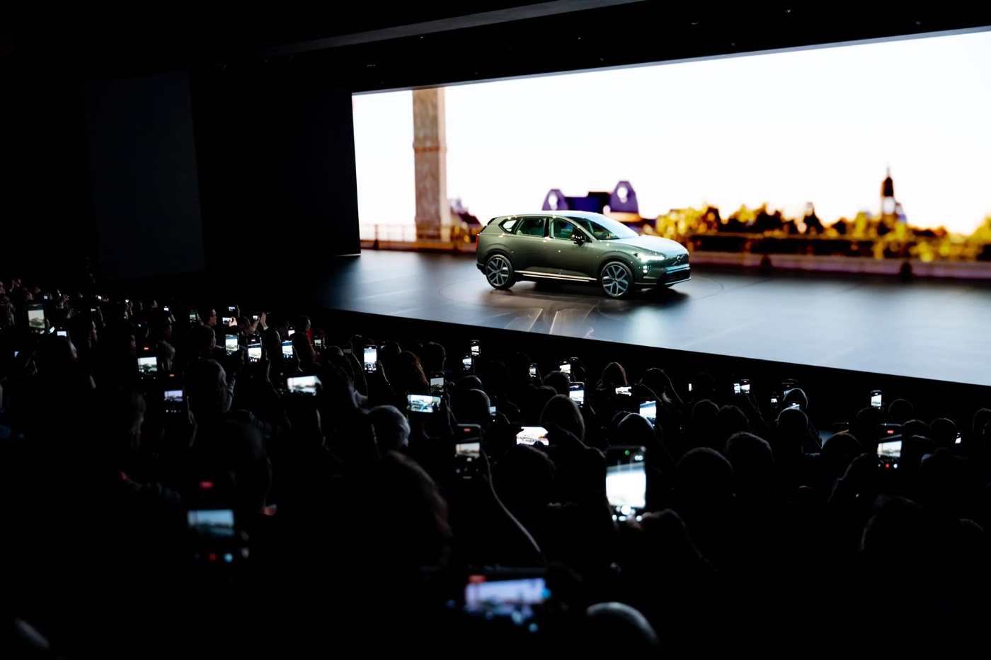 Elektrischer SUV wird auf einer Bühne präsentiert, das Publikum fotografiert mit Smartphones.