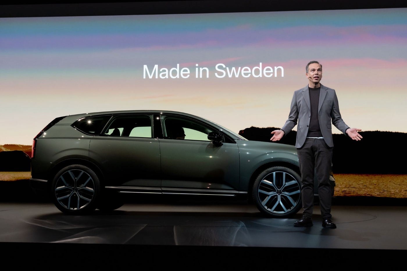 Ein Mann präsentiert einen elektrischen SUV auf der Bühne, im Hintergrund steht „Made in Sweden“.