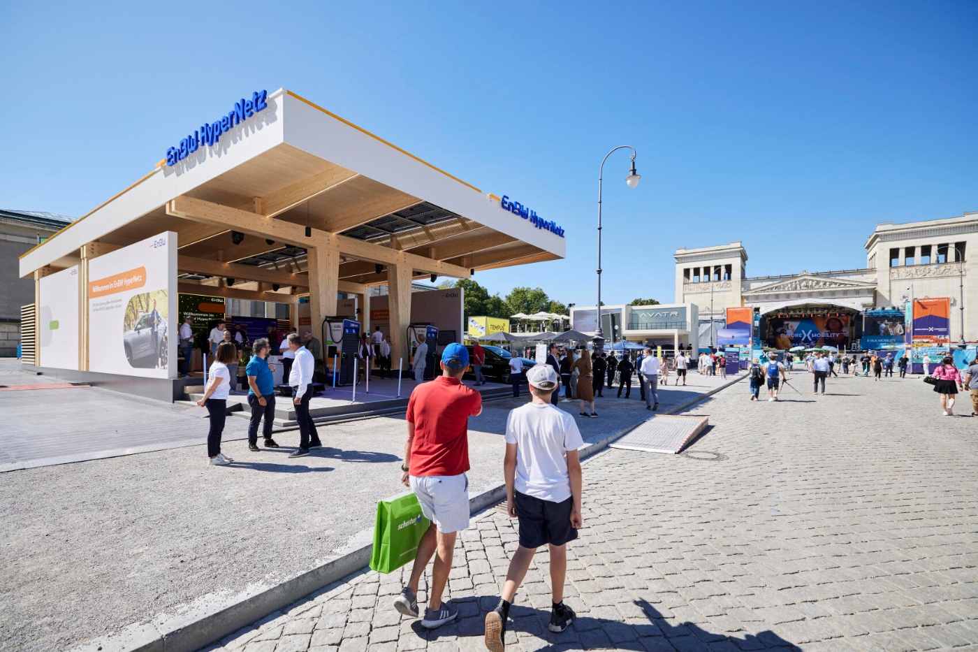 Visitors walk between exhibition pavilions at an outdoor trade show.