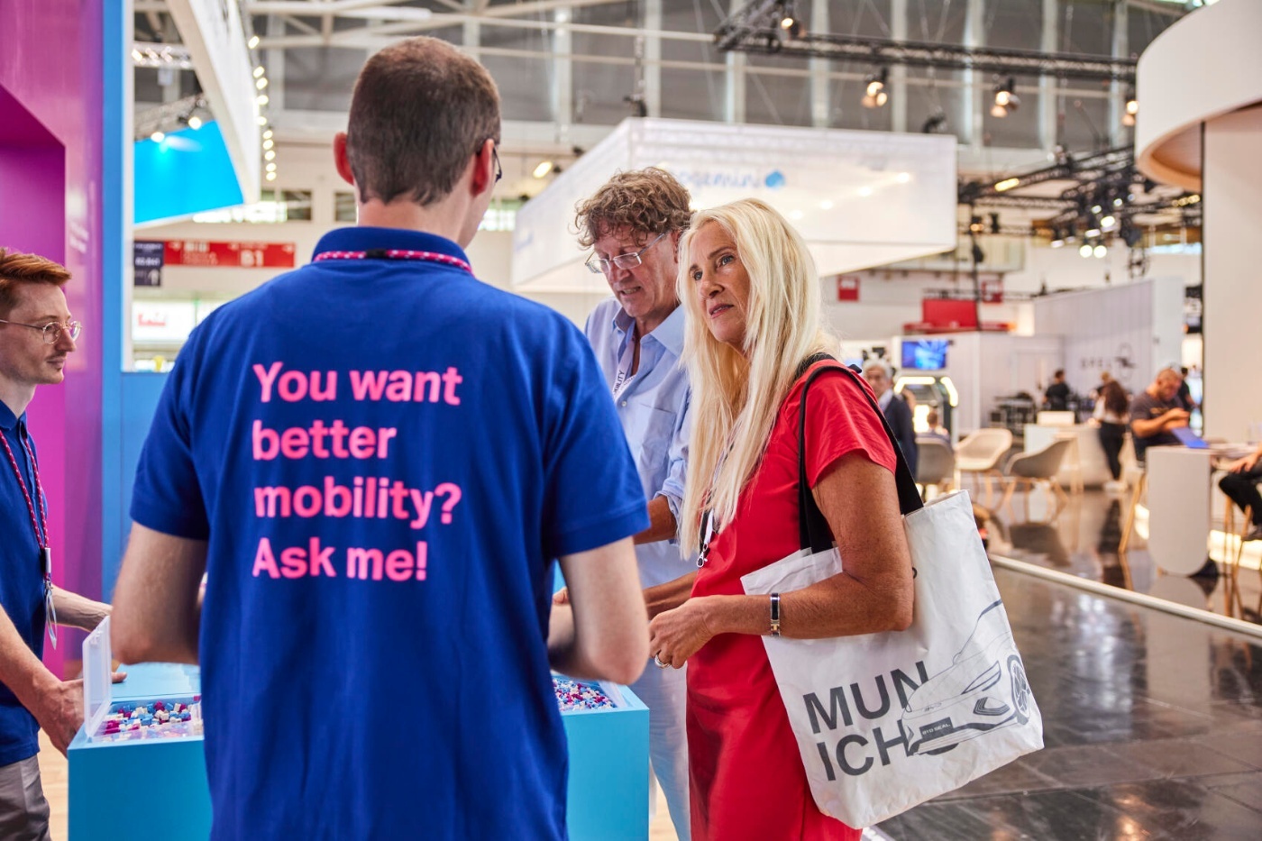 Messemitarbeiter spricht an einem Messestand mit Besuchern über Mobilität.
