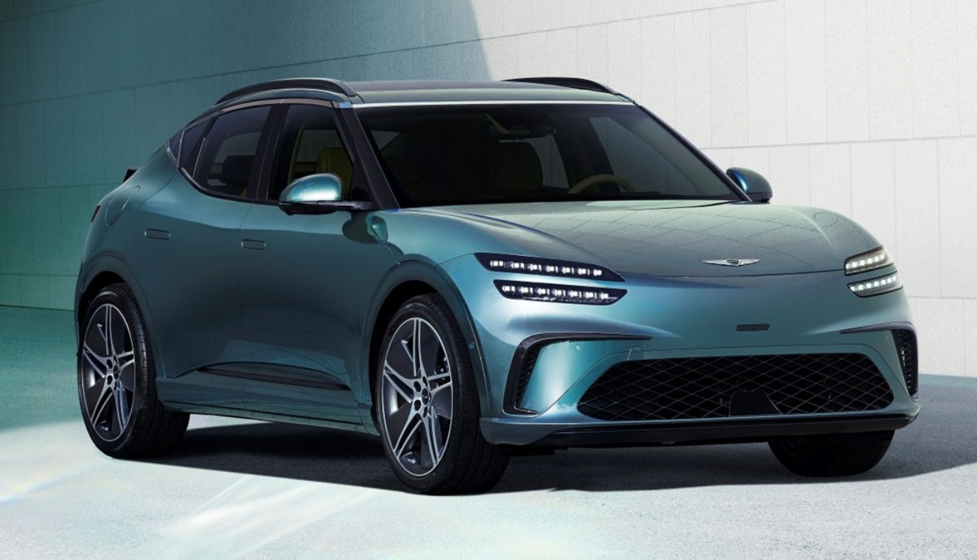 Front-side view of a modern electric SUV parked in front of a light-colored wall, with a sleek design and narrow LED headlights.