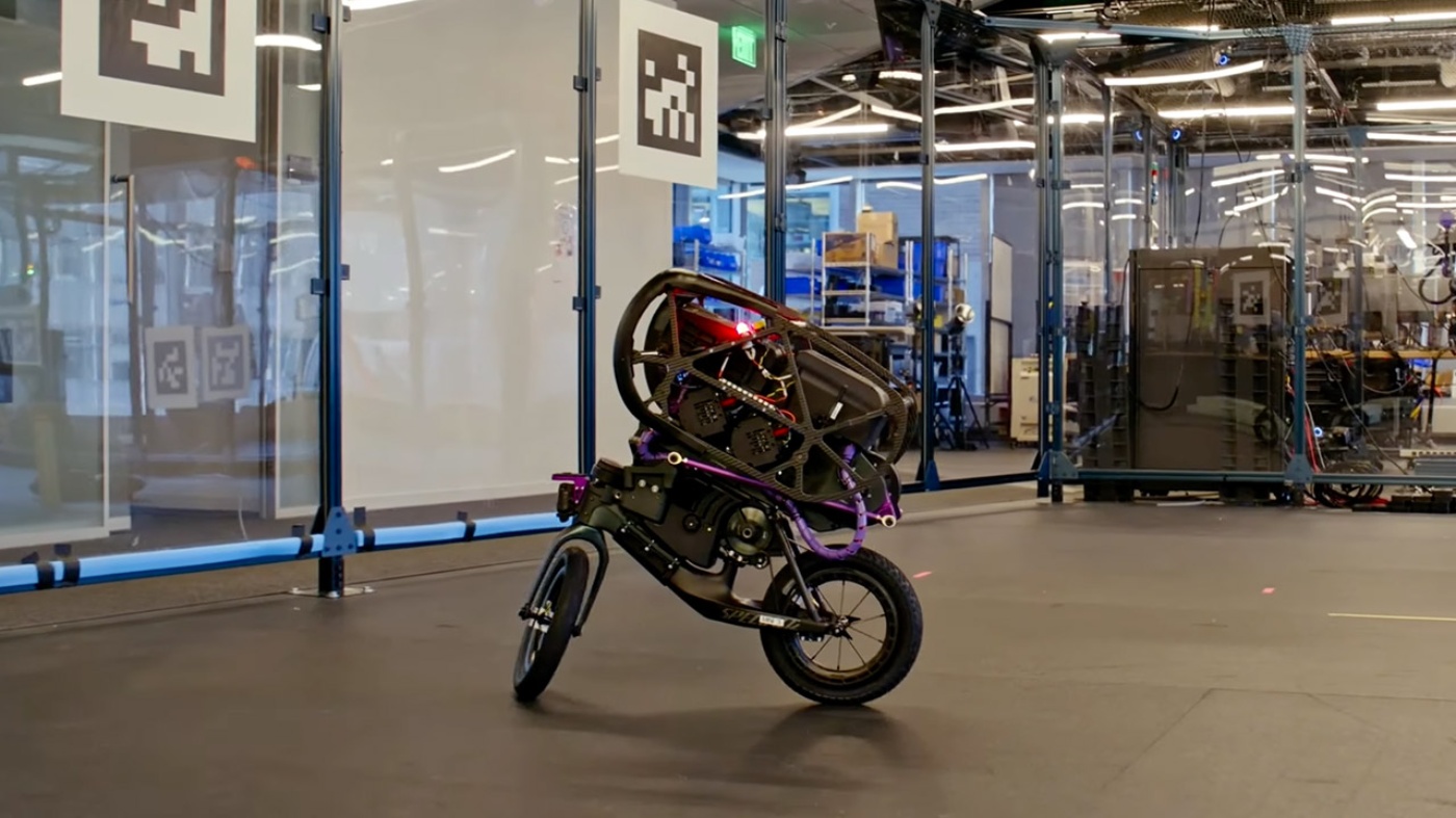 Autonomous self-balancing two-wheeled robot bike inside a research lab, equipped with sensors and a carbon frame.