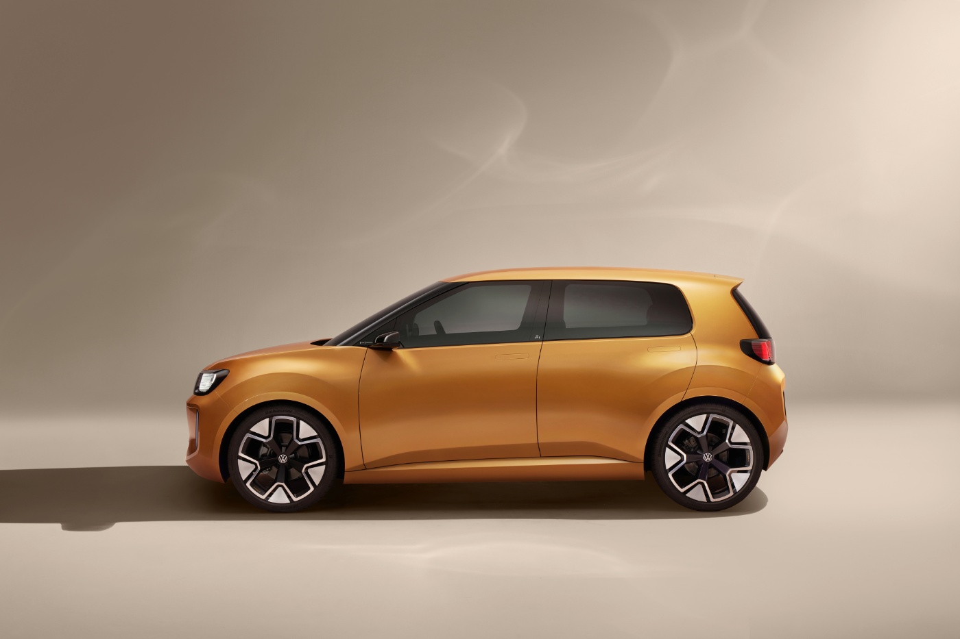 Side view of a golden compact Volkswagen car in a studio setting with soft lighting.