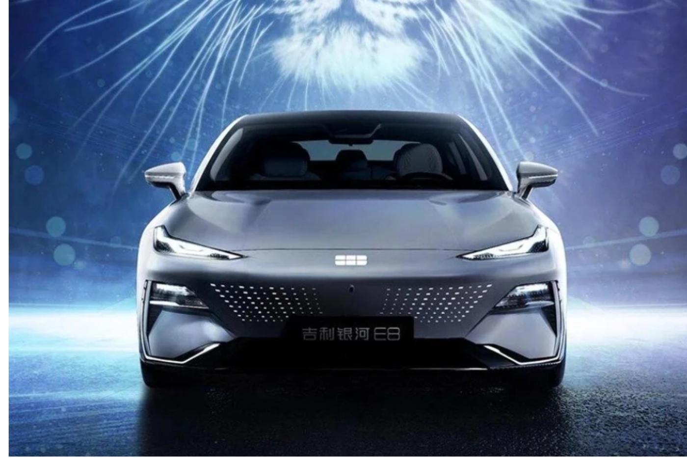 Front view of a silver Geely electric car with illuminated grille and futuristic lighting effects in the background.