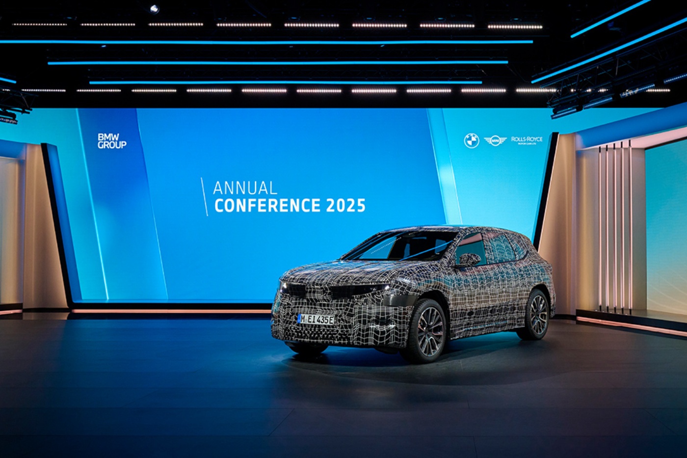 Elektro-SUV-Prototyp mit Tarnfolie, präsentiert auf der Bühne der BMW Group Jahreskonferenz 2025.