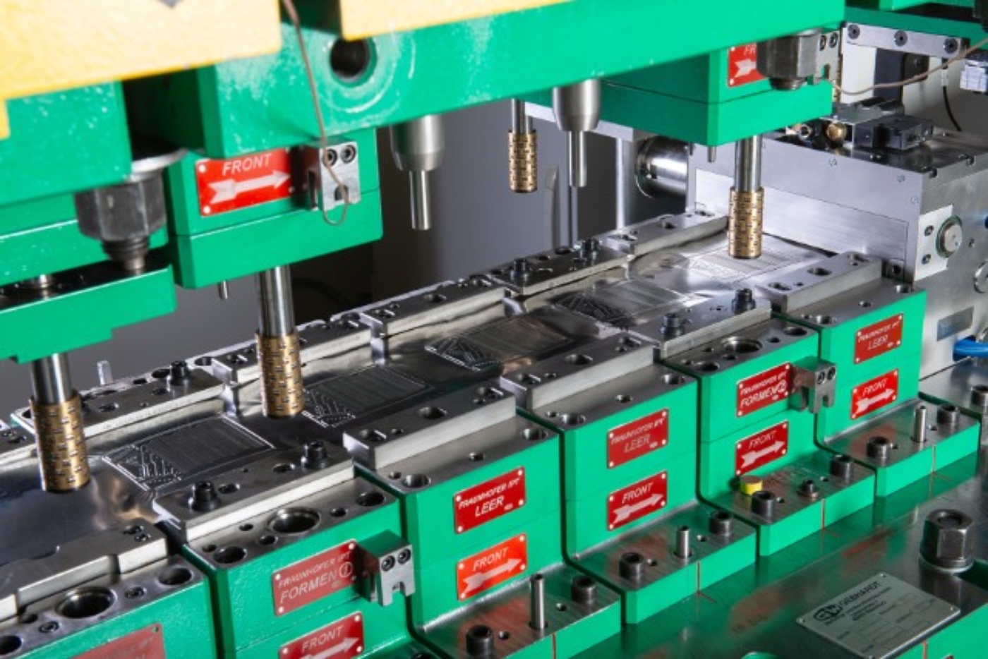 Nahaufnahme eines grünen Industrie-Stanzwerkzeugs für hochpräzise Metallumformungen.