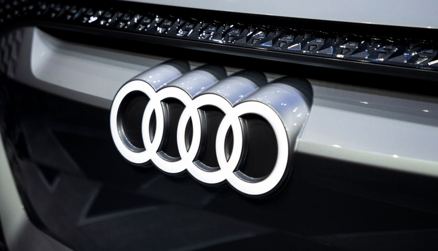 An Audi concept electric vehicle is showcased on stage, featuring a modern design with illuminated accents.