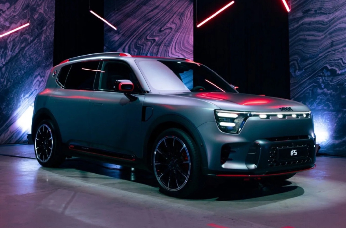 Elektrischer SUV von Smart mit futuristischer Beleuchtung wird in einem Raum mit roten und violetten Lichtakzenten präsentiert.
