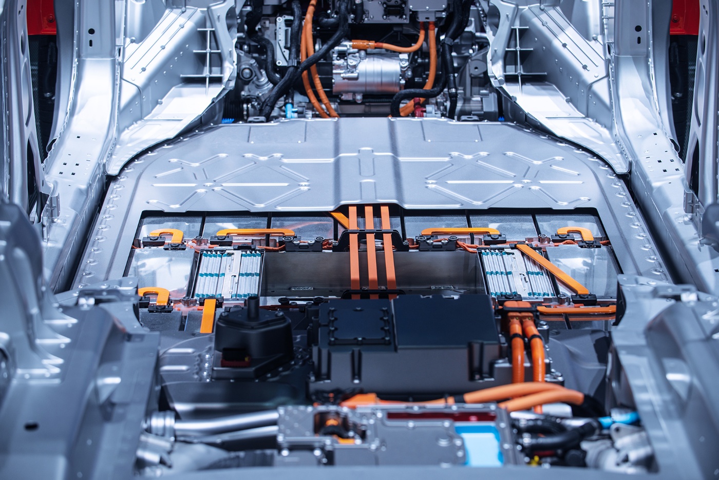Interior view of an electric vehicle chassis showing the battery system and high-voltage orange cables.